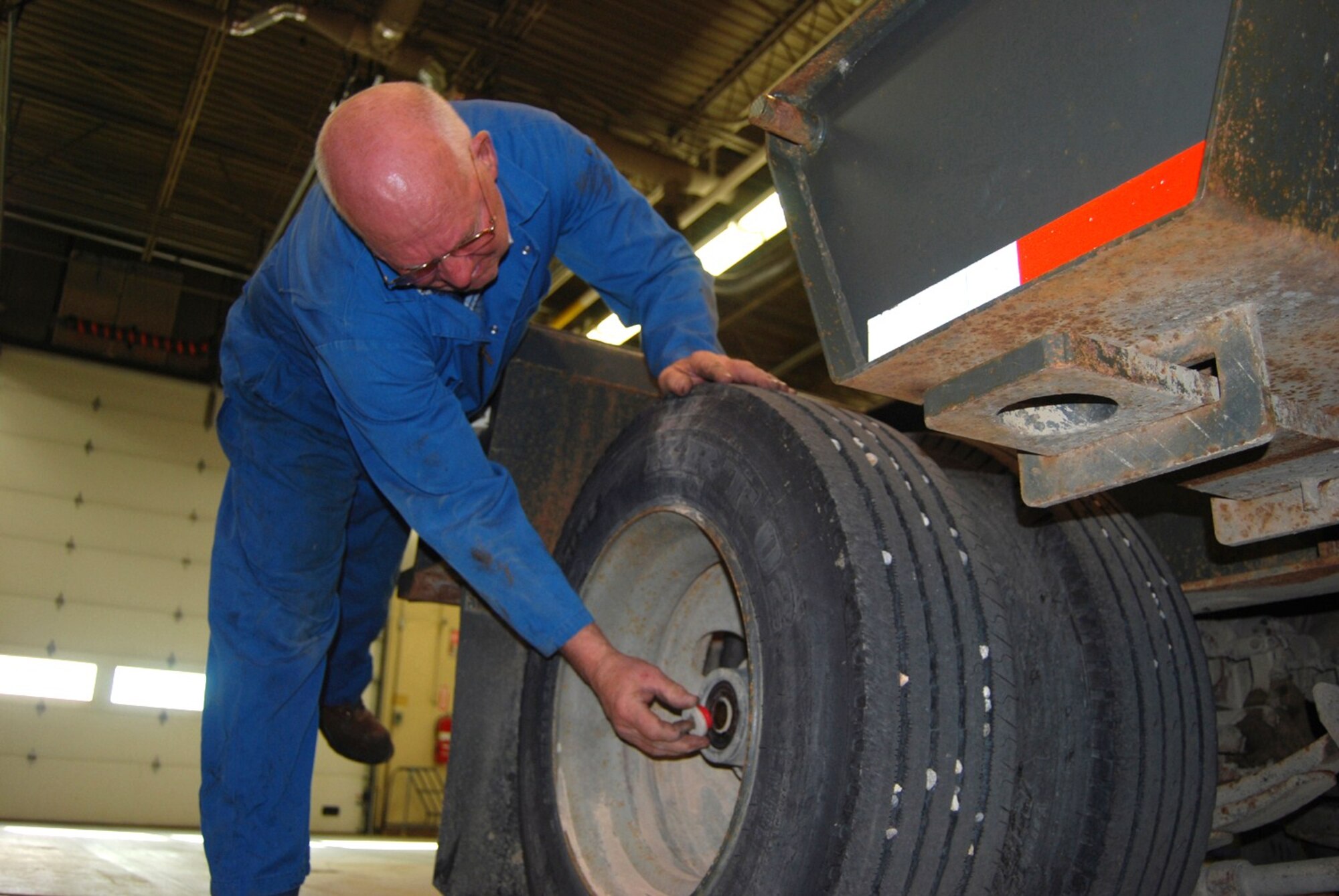 Allyn Hill, 341st Logistics Readiness Squadron mechanic, checks the tires of a flat-bed trailor. Mr. Hill has been working in LRS for 40 years and is retiring in May. (U.S. Air Force photo/Airman 1st Class Kristina Overton)