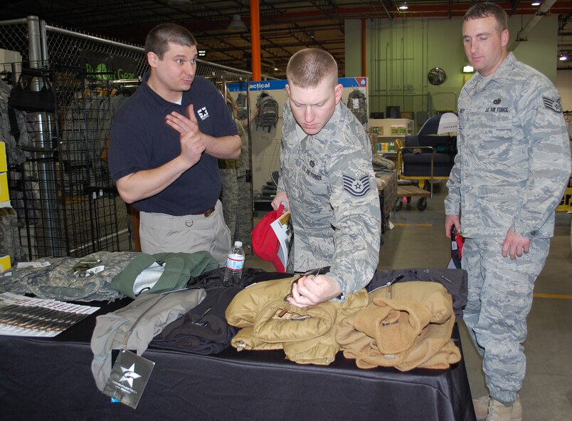 Tech. Sgt. Martin Hanenburg and Staff Sgt. Bryan Bailey, Heating, Ventilation and Air Conditioning technicians wiht the 819th RED HORSE Squadron, look over some new uniform accessories. Vendor for PROPPER Andrew Moore explains some of the features of the new jacket during the Vendor's Fair March 24 at the base service store. (U.S. Air Force photo/Valerie Mullett)