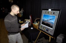 MINOT, N.D. -- 1st Lt. Shawn Adams, 5th Bomb Wing unit deployment manager, looks at a B-52H Stratofortess painting during the silent auction at the 24th Annual Prairie Warrior Association Auction March 27. The auction allows military members and Minot area locals to come together and support the Team Minot family. (U.S. Air Force photo by Senior Airman Benjamin Stratton)