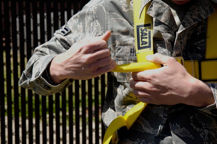 U.S. Air Force Airman 1st Class Amos Hommel tightens his harness while preparing to climb the radio tower on Joint Base Charleston, S.C., March 23, 2010. When climbing the tower it is required to wear a harness which provides support across the lower chest, over the shoulders and around the climber's legs. Airman Hommel is a radio frequency transmission systems specialist with the 628th Communications Squadron. (U.S. Air Force Photo/Airman 1st Class Lauren Main)