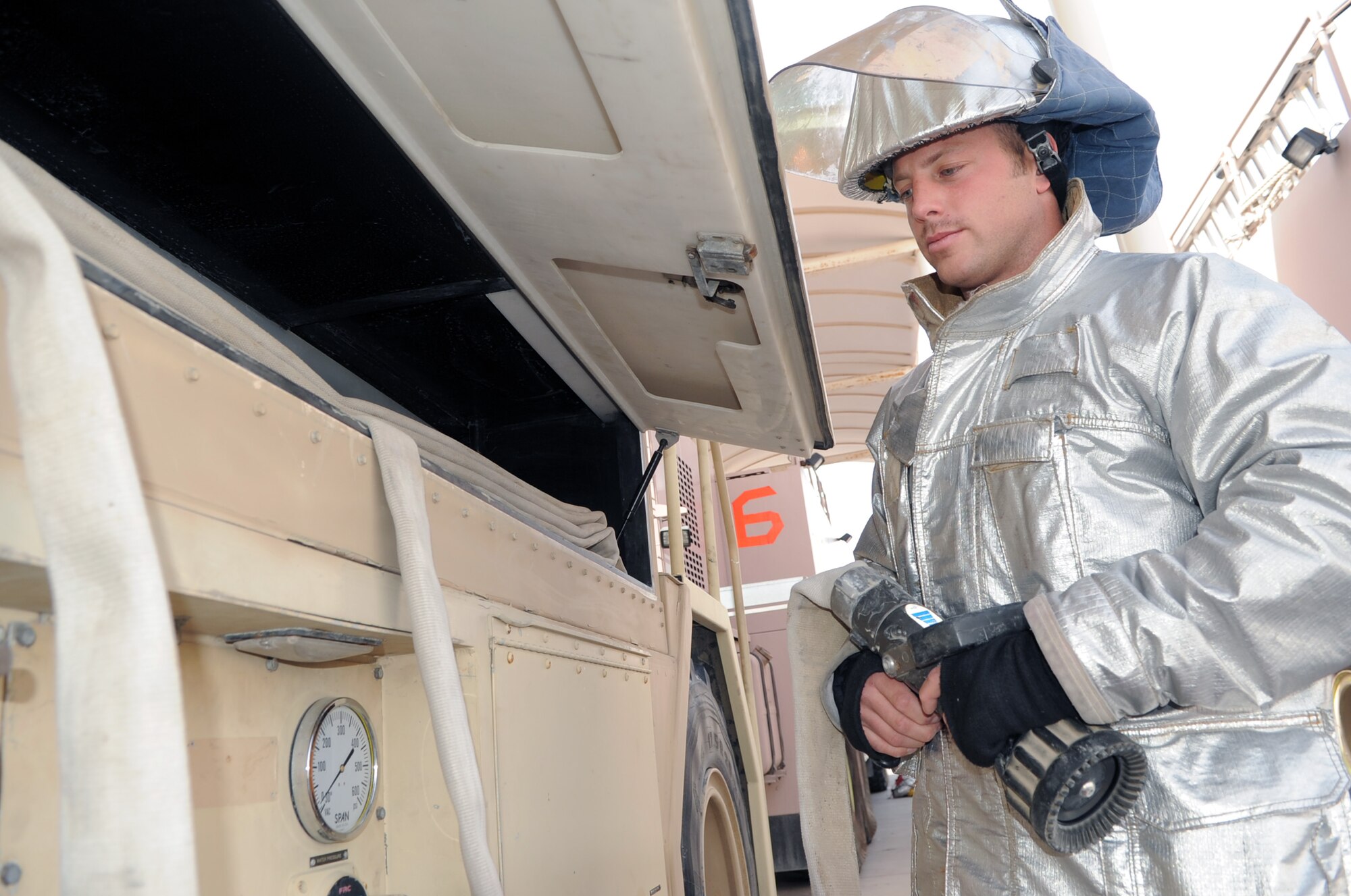 Airman 1st Class Kevin Collins, an Air Force firefighter deployed with the 380th Expeditionary Civil Engineer Squadron fire department, moves a hose from his fire truck during operations at a non-disclosed base in Southwest Asia on March 29, 2010. As an emergency responder, Airman Collins and his fellow firefighters are responsible for protecting thousands of deployed personnel and billions of dollars of Air Force assets from fire. He is deployed from the 9th Civil Engineer Squadron at Beale Air Force Base, Calif., and his hometown is Gilroy, Calif. (U.S. Air Force Photo/Master Sgt. Scott T. Sturkol/Released)