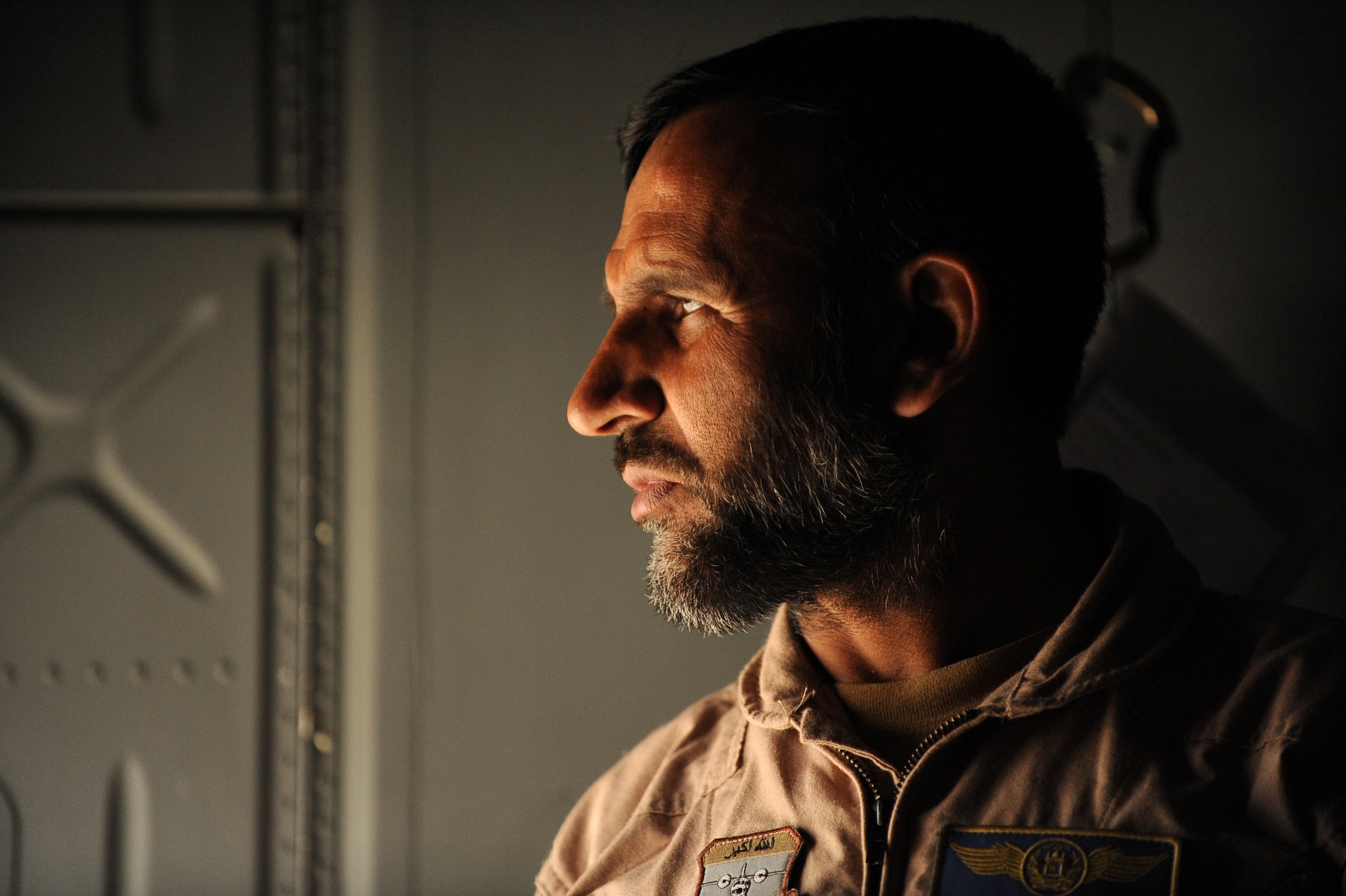 Afghanistan National Army Air Corps Master Sgt. Sheer Aqa Karimi, a C-27A Spartan Loadmaster, looks out the crew door of a C-27 prior to take-off for his check ride, March 28, 2010, at Kabul International Airport, Afghanistan.  (U.S. Air Force/ Staff Sgt. Manuel J. Martinez/released) 