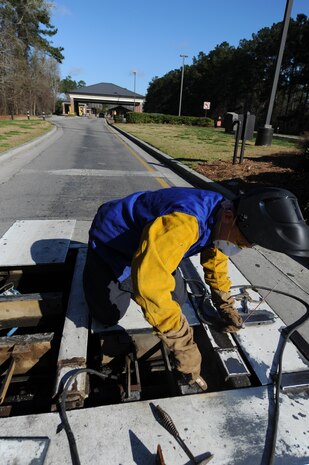 U.S. Air Force Master Sgt. Daniel Martin uses a wire brush to remove slag, which is the residue leftover after welding, from the pop-up security barrier at the inbound Rivers Avenue gate entrance on Joint Base Charleston, S.C., March 23, 2010. Sergeant Martin was at the gate to weld more steel to the barrier for reinforcement. Sergeant Martin is the NCO in charge of the structure shop with 628th Civil Engineer Squadron. (U.S. Air Force photo/James Bowman/released)
