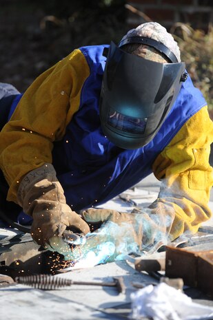 U.S. Air Force Master Sgt. Daniel Martin welds steel onto the pop-up security barrier at the inbound Rivers Avenue gate entrance at Joint Base Charleston, S.C., March 23, 2010. Sergeant Martin was at the gate to weld more steel to the barrier for reinforcement. Sergeant Martin is the NCO in charge of the structure shop with 628th Civil Engineer Squadron. (U.S. Air Force photo/James Bowman/released)