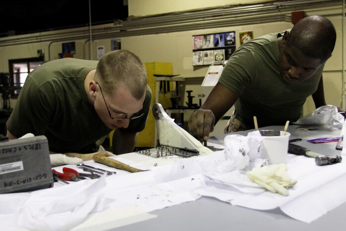 Lance Cpl. Scott Hutton and Lance Cpl. Thomas Boyd, Marine Aviation Logistics Squadron 12 aviation structural mechanics, work at finding the right screws to use on an avionics part at the MALS-12 airframes warehouse here March 30. MALS-12 airframe mechanics are responsible for the operation of the aircraft here by maintaining and replacing parts on the aircraft when necessary.
