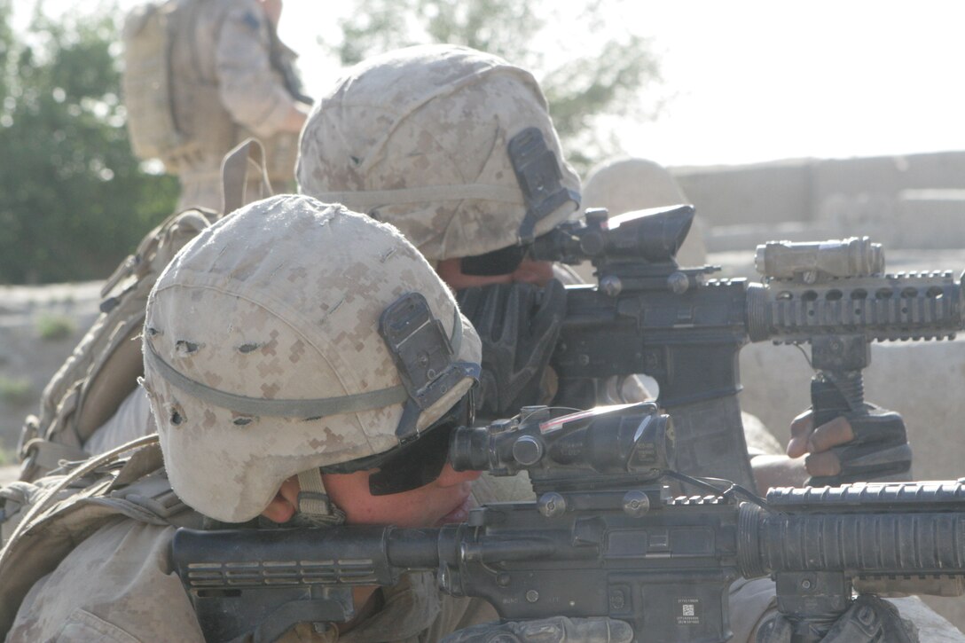 Cpl. Erick A. Monterrosa, background, a radio operator with Weapons Company, 2nd Battalion, 2nd Marine Regiment, and Lance Cpl. Justin K. Schwartz, foreground, look through their rear sight optics on their M-4 Carbine rifles while patrolling in Laki, Garmsir District, Helmand province, Afghanistan, March 31. With Explosive Ordnance Disposal technicians in support, the Marines used mine detectors to check a bridge and tree lines for improvised explosive devices that sat no more than 50 meters away from the patrol base.