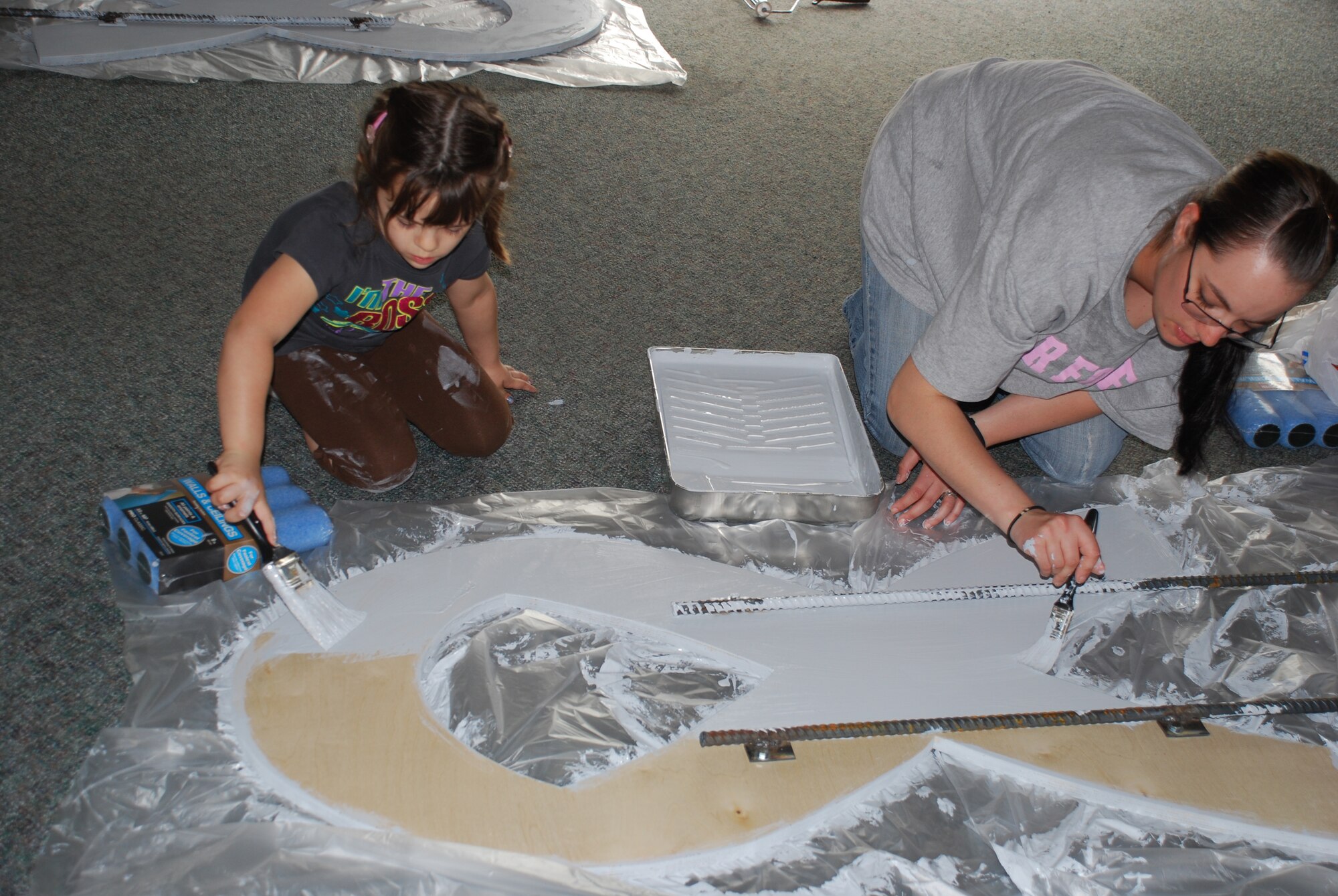 Kristin Gallego (left), 4-year-old volunteer, and Airman Katherine McKenna (right), 383rd Training Squadron Airman in Training, paint gray primer on a ribbon that symbolizes Sexual Assault Awareness Month March 27. The ribbons were later painted teal and were displayed at each of the gates March 31 on Sheppard Air Force Base, Texas. (U.S. Air Force photo/Airman 1st Class Valerie Hosea)
