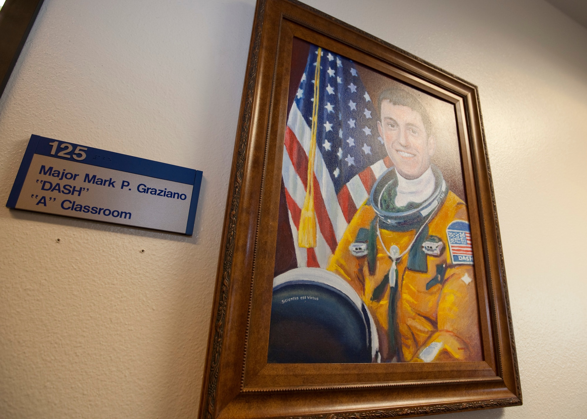 A portrait of Maj. Mark "Dash" Graziano hangs in front of the entrance to the Alpha classroom at the USAF Test Pilot School.  The TPS held a ceremony March 19 to dedicate the classroom to Major Graziano.  
