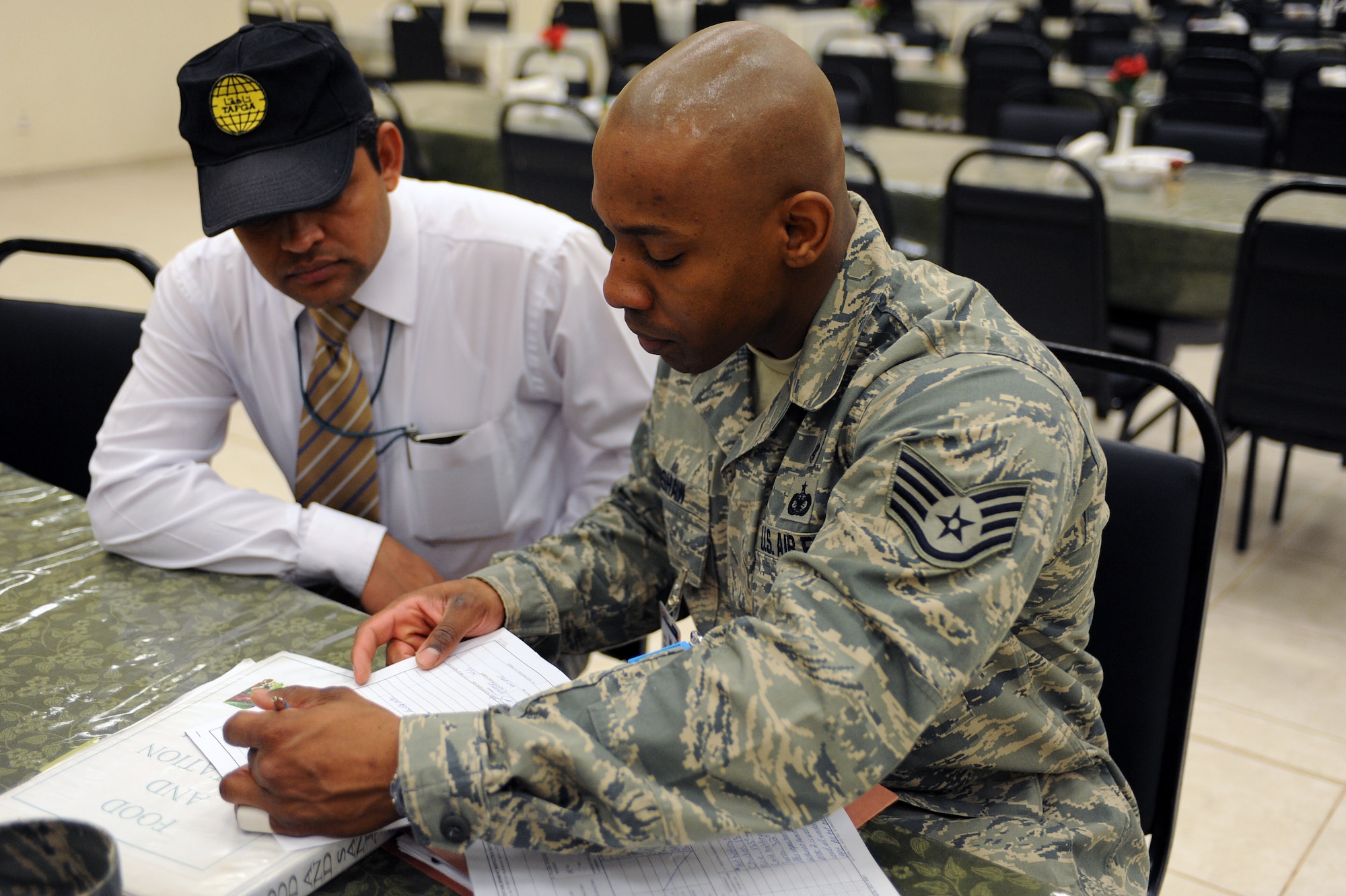 Staff Sgt. William Crenshaw 332nd Aerospace Medicine Squadron public health noncommissioned officer in charge, reviews comments with the Dining Facility Two manager after a successful inspection of the facility at Joint Base Balad, Iraq, March 23, 2010. Public Health personnel conduct up to eight no-notice facility inspections every month on JBB to ensure standards are being met. Sergeant Crenshaw is deployed from Joint Base San Antonio, and is a native of Long Beach, Calif. (U.S. Air Force photo by Master Sgt. Linda C. Miller/Released)