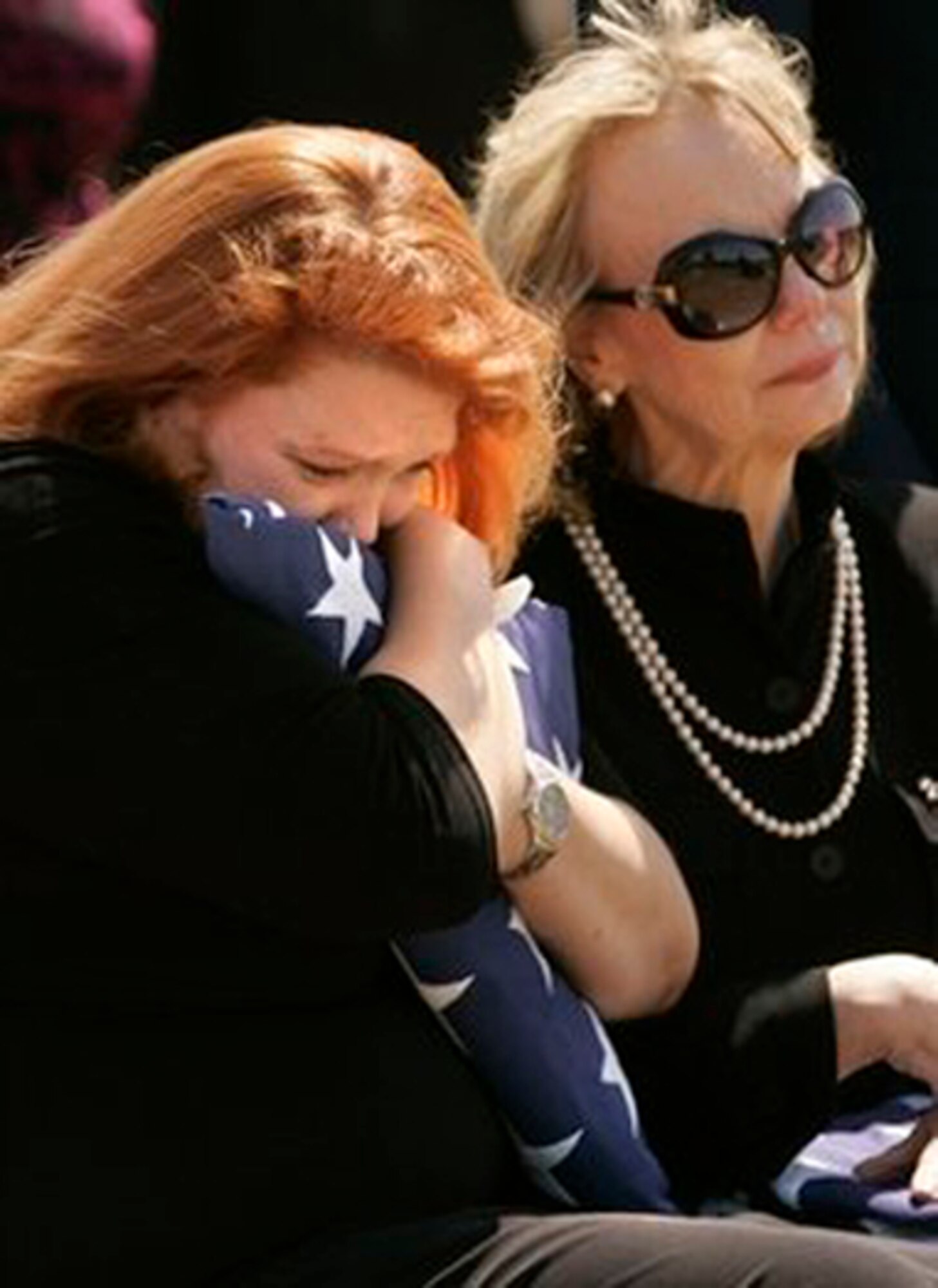 Christy Hollerich, left, holds a flag as her mother Susan Miller looks on at the funeral of Air Force Maj. Curtis Daniel Miller on Monday, March 29 in Dallas. Maj. Miller, of Palacios, Texas, was buried Monday afternoon at Dallas-Fort Worth National Cemetery, with full military honors. His funeral comes 38 years to the day after his gunship was shot out of the sky over Laos during the Vietnam War. His remains were processed at the Air Force Mortuary Affairs Operations Center at Dover Air Force Base, Del. (AP Photo/Mike Fuentes)