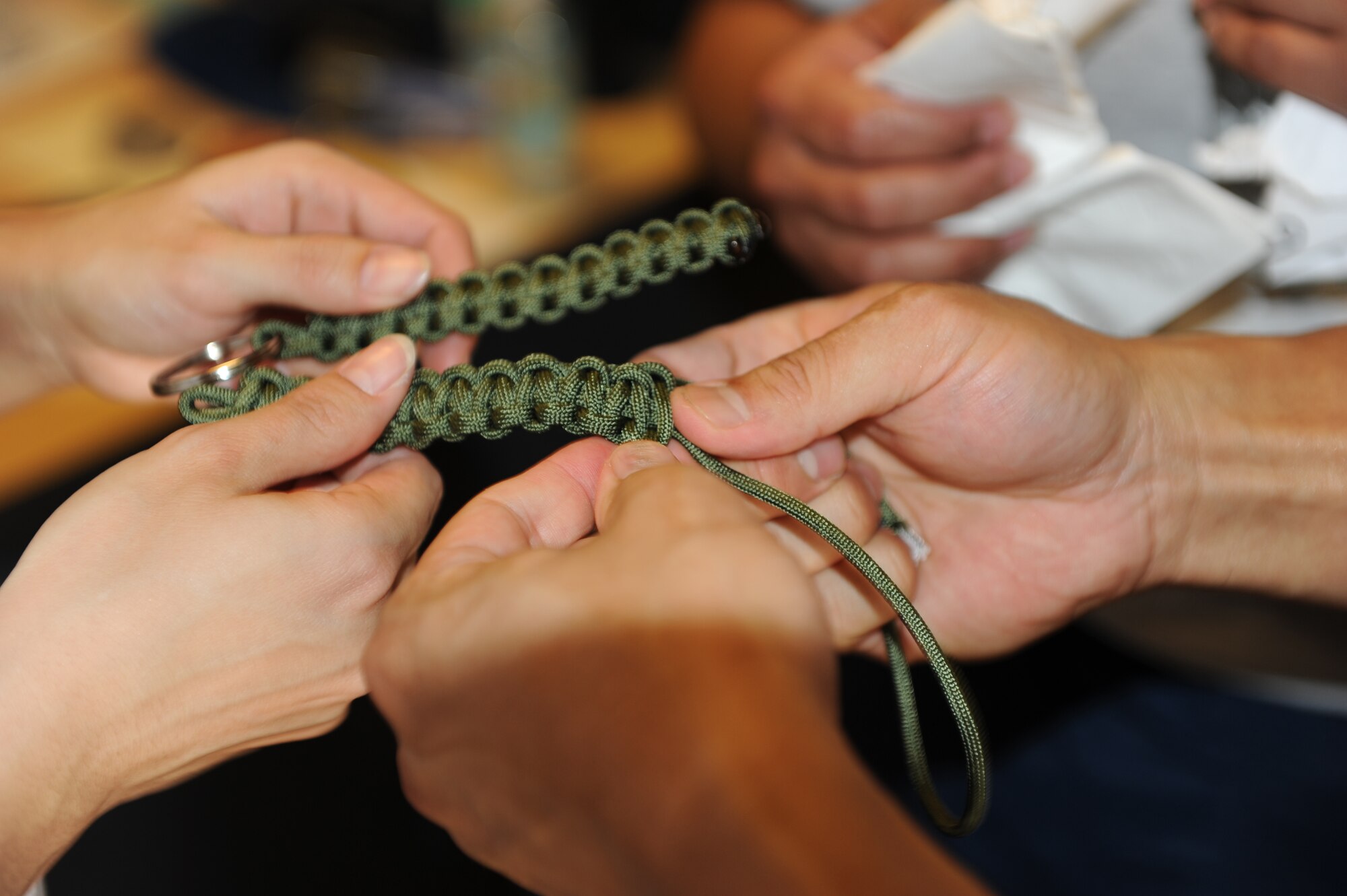 Servicemembers braid key chains at the Air Force Chaplains office as one of nine challenges during The Amazing Race Afghanistan sponsored by the 455th Expeditionary Force Support Squadron morale, welfare and recreation office, March 28, 2010. (U.S. Air Force photo by/ Capt. Jean Duggan)