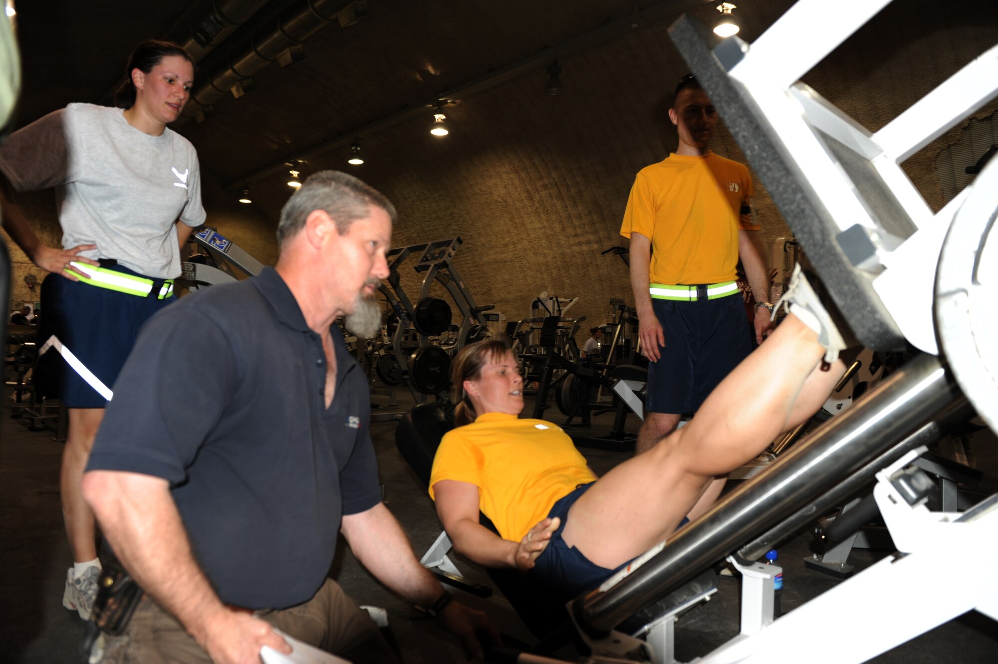 Richard Miller, 455th Expeditionary Force Support Squadron, morale, welfare and recreation supervisor, monitors Team Mixed Company?s progress on a leg press machine during The Amazing Race Afghanistan, March 28, 2010. This challenge required teams to leg press a combined weight of 10,000 pounds. (U.S. Air Force photo by/ Capt. Jean Duggan)