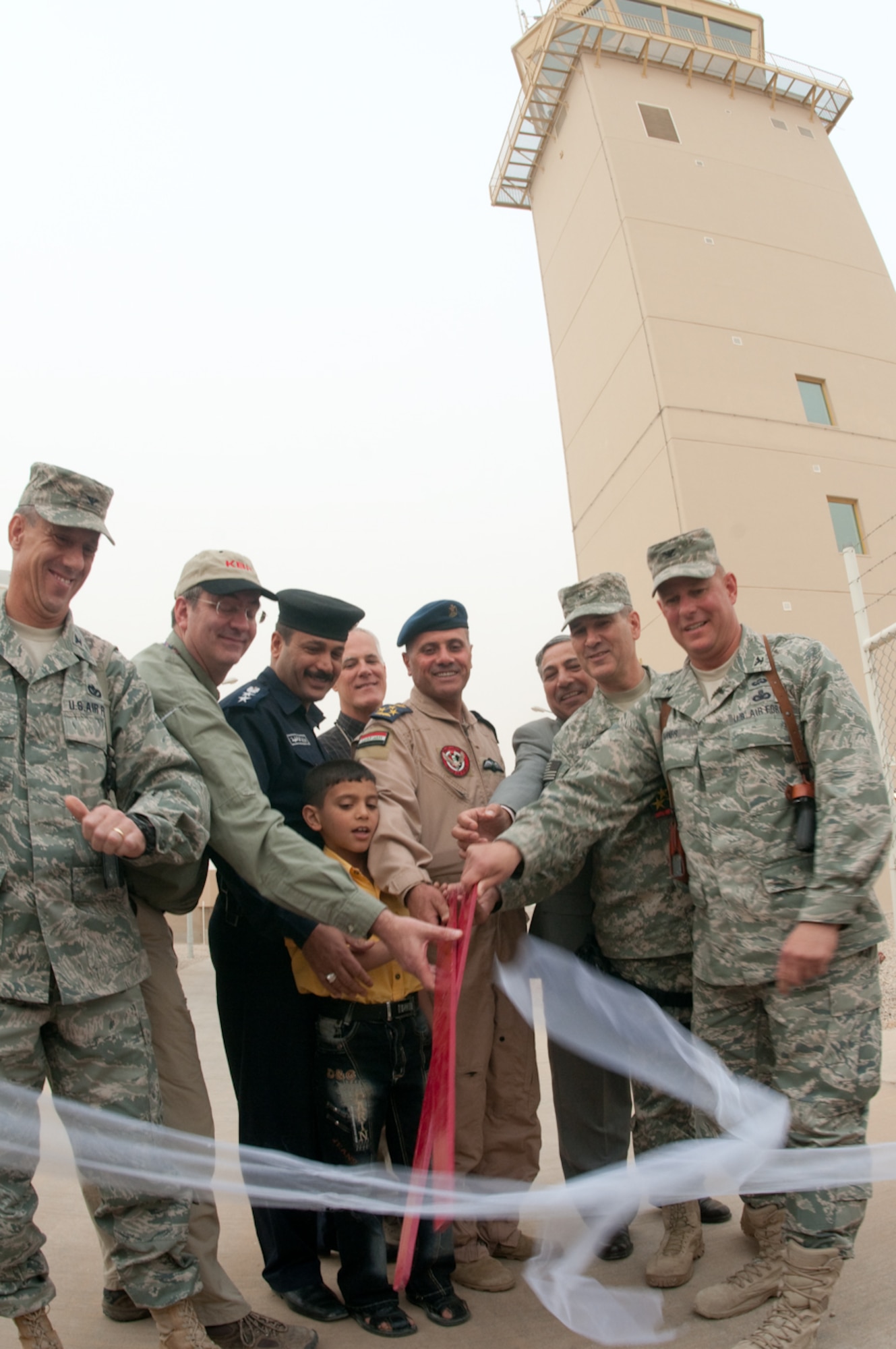 U.S. and Iraq forces join together along with KBR, contract builders, to cut
the ribbon during the Ali Base Airfield Commemoration Day to officially open
the brand new air traffic control tower in the background at Ali Base, Iraq
March 27, 2010. The $61.7 million ATC tower is the most modern tower built
in Iraq standing 104 feet tall. (U.S. Air Force photo by Senior Master Sgt.
Elizabeth Gilbert)
