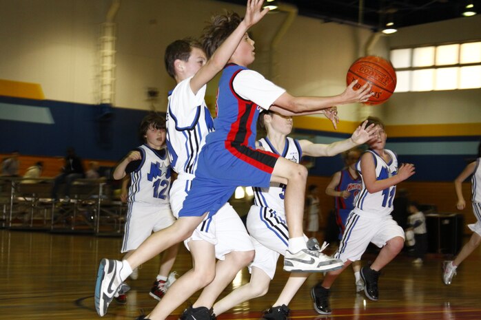 A Knicks player goes for a layup against several Magic players during a youth basketball game at the IronWorks Gym here March 30. The Knicks won by two points making them the regular season champions .