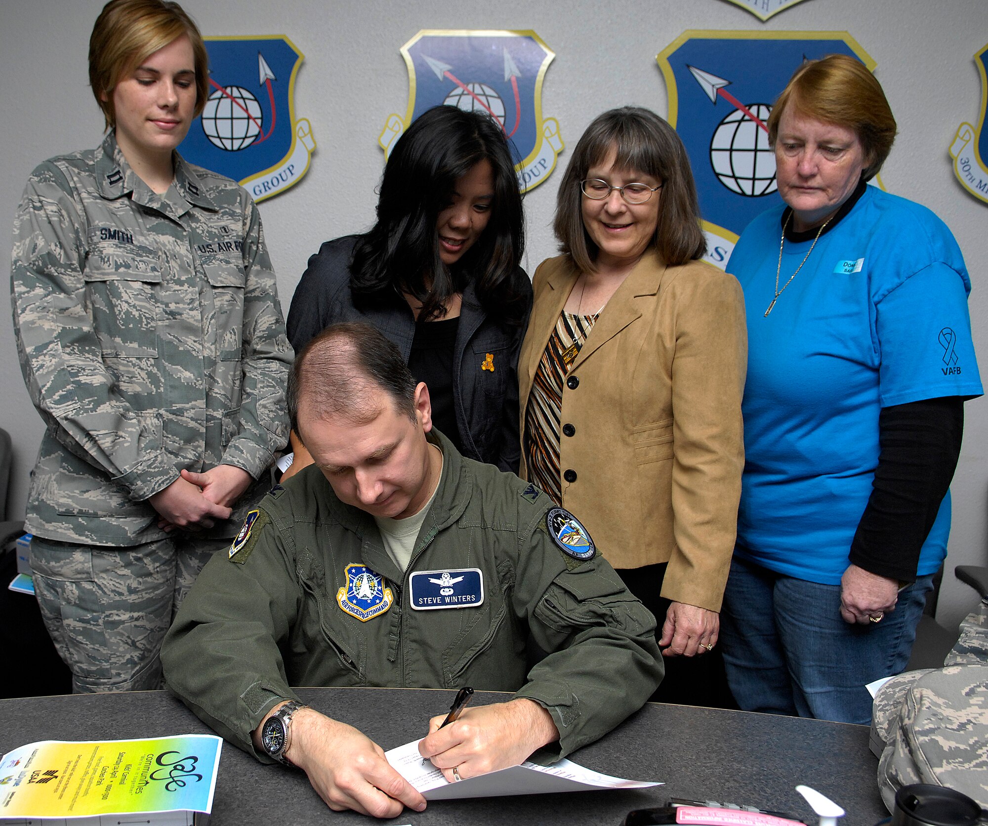 VANDENBERG AIR FORCE BASE, Calif. --  Col. Steven Winters,  the 30th Space Wing vice commander, signs the April Awareness Month proclamation here Wednesday, March 31, 2010. (From left to right) Capt. Jodi Smith, from the 30th Medical Operations Squadron, Ms. Pauline Chui, Vandenberg's Family Advocacy outreach manager, Ms. Sally Galligan, the Airman and Family Readiness Center chief, and Ms. Donna Rathbun, the Sexual Assault Response coordinator, stand behind Colonel Winters as he signs the proclamation. During the month of April, Vandenberg has pledged to recognize Child Abuse Prevention Month, Sexual Assualt Prevention Month and Alcohol Awareness Month. (U.S. Air Force photo/Airman 1st Class Andrew Lee)