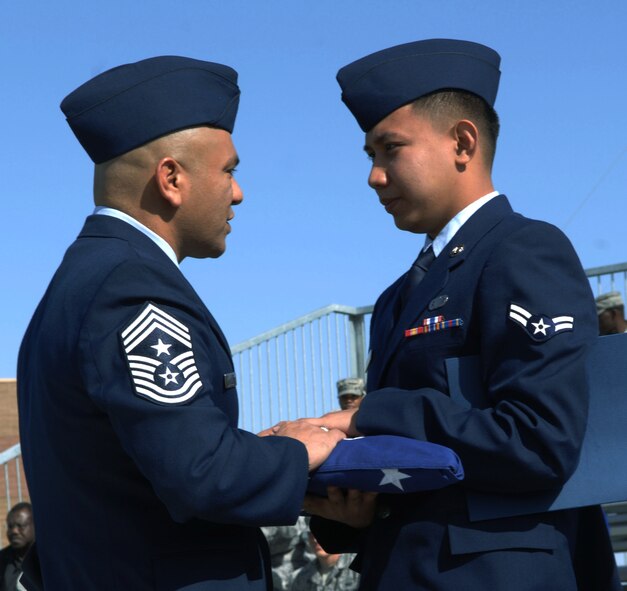 HOLLOMAN AIR FORCE BASE, N.M. -- Airman 1st Class Vincent Bulatao, 49th Comptroller Squadron, receives a folded American flag from 49th Fighter Wing command chief, Chief Master Sgt. Gerardo Tapia during a Naturalization Ceremony, March 26, 2010 at Heritage Park. Airman Bulatao, originally from the Philippines, has served in the U.S. Air Force since November 2008. Since September 2001, more than 53,000 U.S. armed forces members have been naturalized by the U.S. Citizenship and Immigration Services. (U.S. Air Force photo by Airman 1st Class Joshua Turner)(Released)