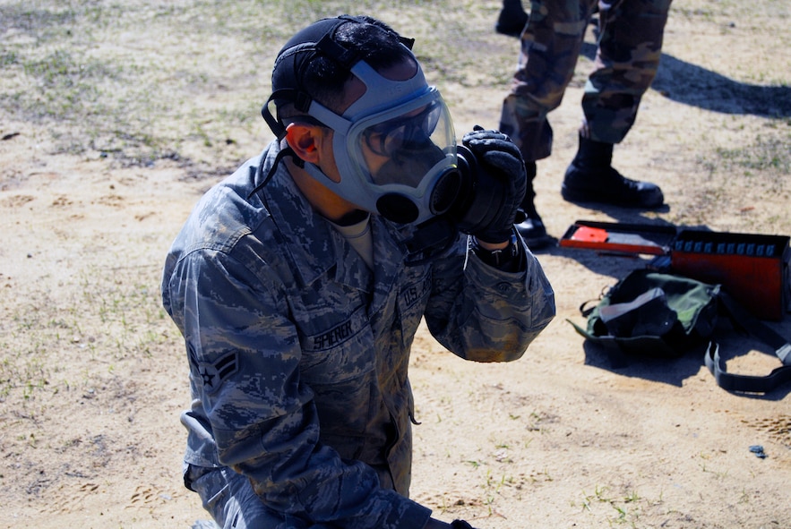 Airman 1st Class Joshua Spierer, 3rd Aerial Port Squadron, clears his gas mask prior to taking hold of his M-16 rifle during the Combat Arms training course March 30. Wearing a gas mask during live-fire training allows students to simulate situations that could be encountered in a deployed location. (U.S. Air Force photo/Senior Airman Quentin Irvin)