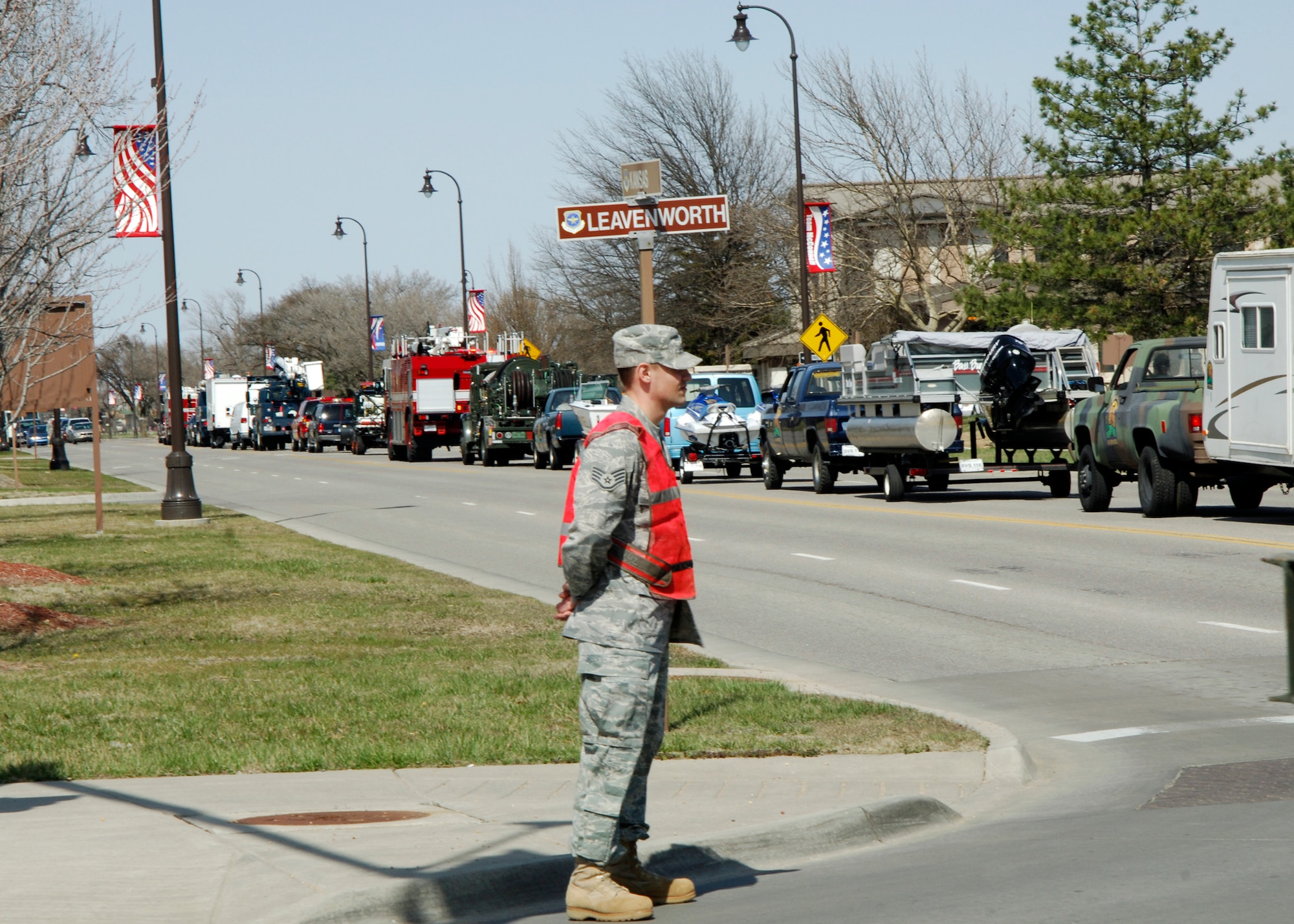 A Team McConnell NCO posts as a road guard while 40 mobility and emergency vehicles from the 22nd Mission Support Group, participate in a pass-in-review through the streets of McConnell Air Force Base, Kan, March 26, 2010. The display was held to demonstrate the 22nd MSG capability to the base’s mission. Airmen from the 22nd MSG provide for all mission support services to wing’s more than 3,500 military and civilian members offering security, fire protection, contracting, transportation/supply and fuels, food, lodging, housing, communications, personnel, recreation and facilities management (U.S. Air Force photo/Airman 1st Class Andrea Salazar)