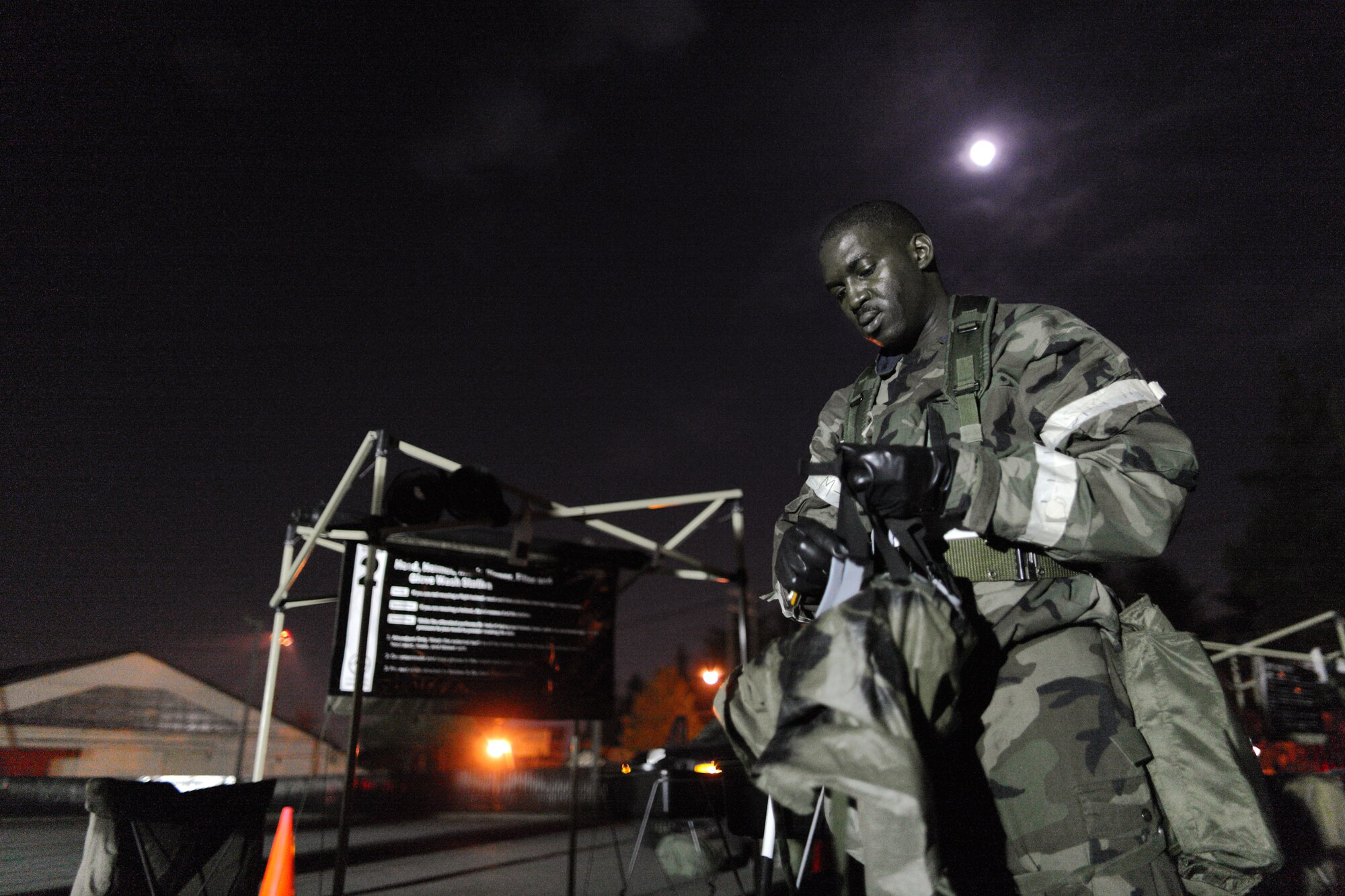 YOKOTA AIR BASE, Japan -- Staff Sgt. Sadiq Stevens, 374th Operation Support Squadron, prepares to don his gas mask at a Contamination Control Point while waiting for simulated contaminated aircrew members arrival here Apr. 01. Yokota conducted an exercise 28 Mar. through 1 Apr. to help maintain operational readiness.  (U.S. Air Force photo/Osakabe Yasuo)