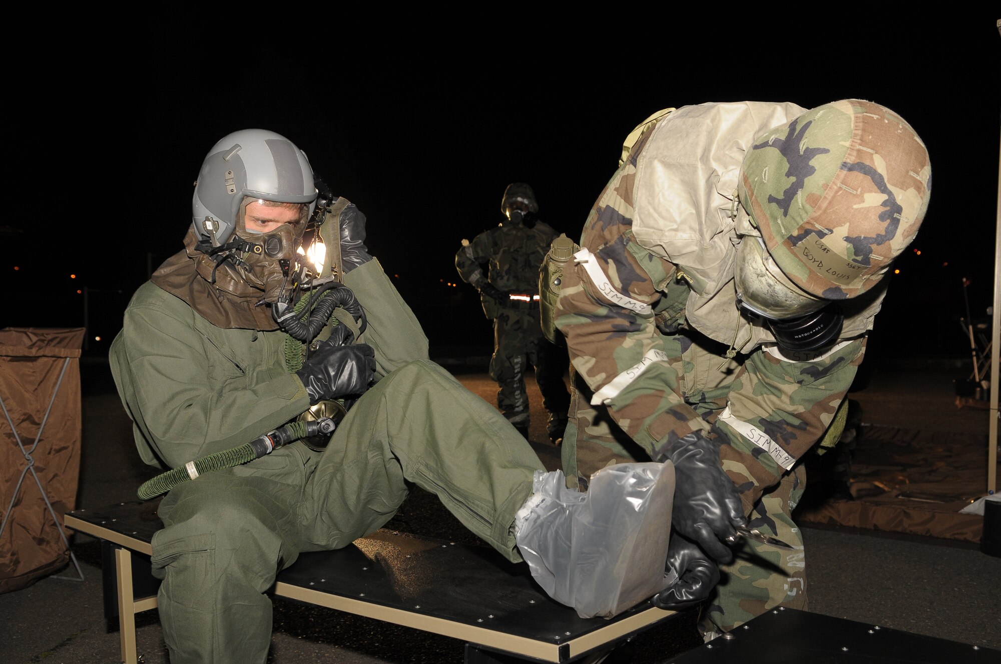 YOKOTA AIR BASE, Japan -- Staff Sgt. Louis Boyd (right), 374th Operations Support Squadron, aircrew life support, removes the boot of 1st Lieutenant Matthew Bryan, 36th Airlift Squadron, during an aircrew decontamination line Mar. 31. The line is used to ensure aircrew are properly decontaminated. (U.S. Air Force photo/ Airman 1st Class Sean Martin)