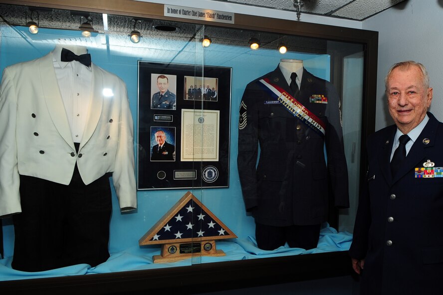 BARKSDALE AIR FORCE BASE, La. -- Chief Master Sgt. James Flascheriem, Charter Chief, poses for a photo beside a display dedicated to him at the Airman Leadership School March 26. Following the unveiling of the display, the students of class 10-4 performed a retreat ceremony in Chief Flascheriem's honor. The Chief donated his white mess dress to the school. The set of mess dress that now resides in the school house is one of only three left in existence. Commandant Master Sgt. Neil Heerdink and ALS instructor Staff Sgt. Allison Cain assembled the display case of the Chief's memorabilia. (U.S. Air Force photo by Senior Airman Joanna M. Kresge)