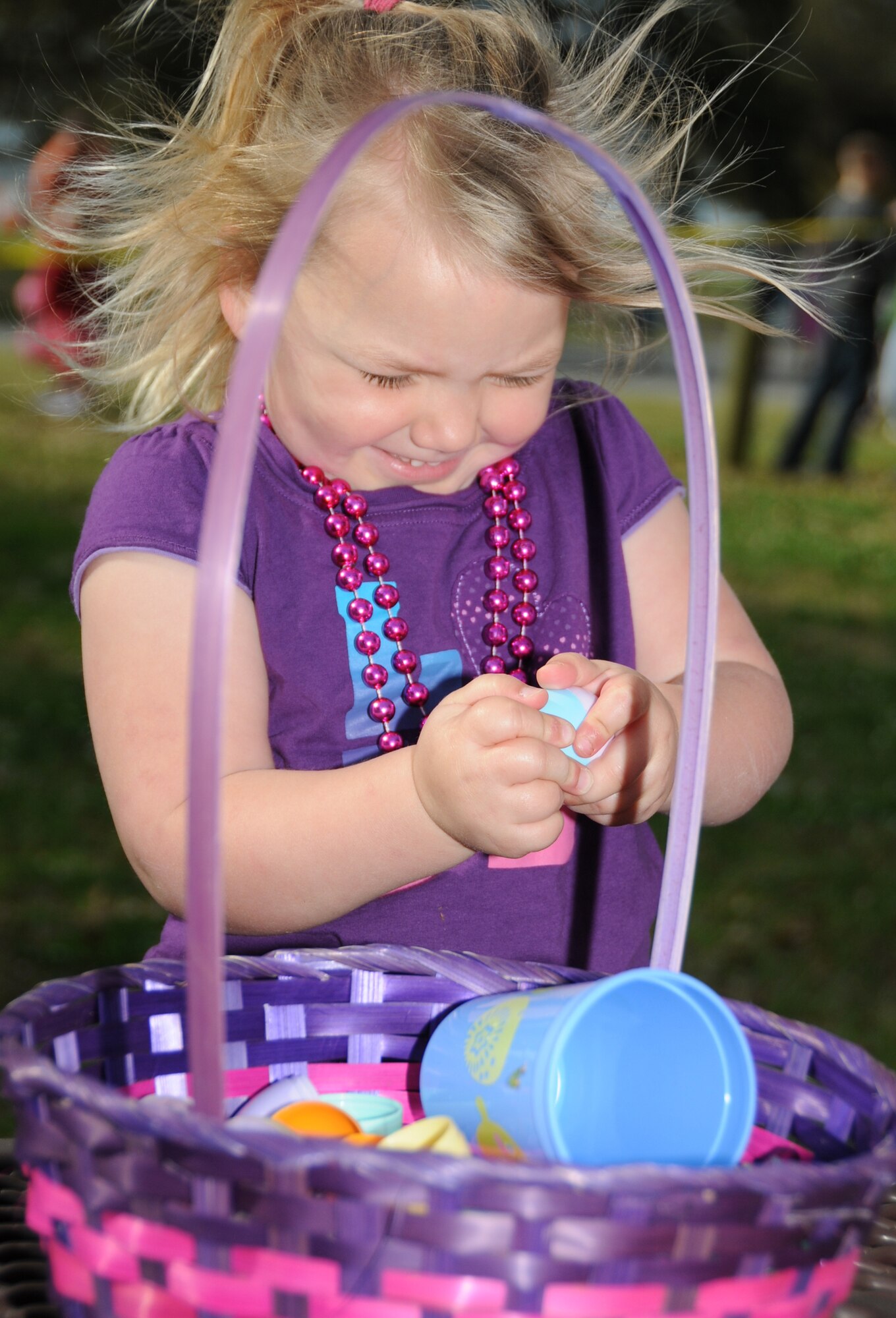 Three-year-old Emma Linge, son of Joshua and Crystal Rands, struggles to open one of her Easter eggs at the egg hunt at marina park.  Her dad is a Seabee currently deployed to Guam.  (U.S. Air Force photo by Kemberly Groue)