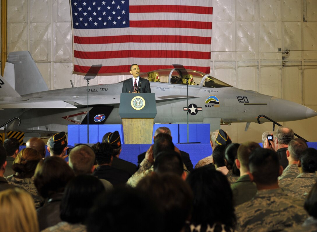 President Barack Obama speaks to a group of service members and honorary guests inside Hangar 3 at Joint Base Andrews, Md., March 31, 2010, about the U.S. expansion and exploration of offshore oil and gas for fuel. The president spoke in front a Navy F/A-18F Super Hornet, which is slated to test the use of environmentally friendly bio fuel on Earth Day, April 22. If the test is successful, the F/A-18F Super Hornet will be the first fighter jet to use a combination of hydrotreated renewable jet and JP-8 fuel to break the sound barrier. (U.S. Air Force photo by Bobby Jones)