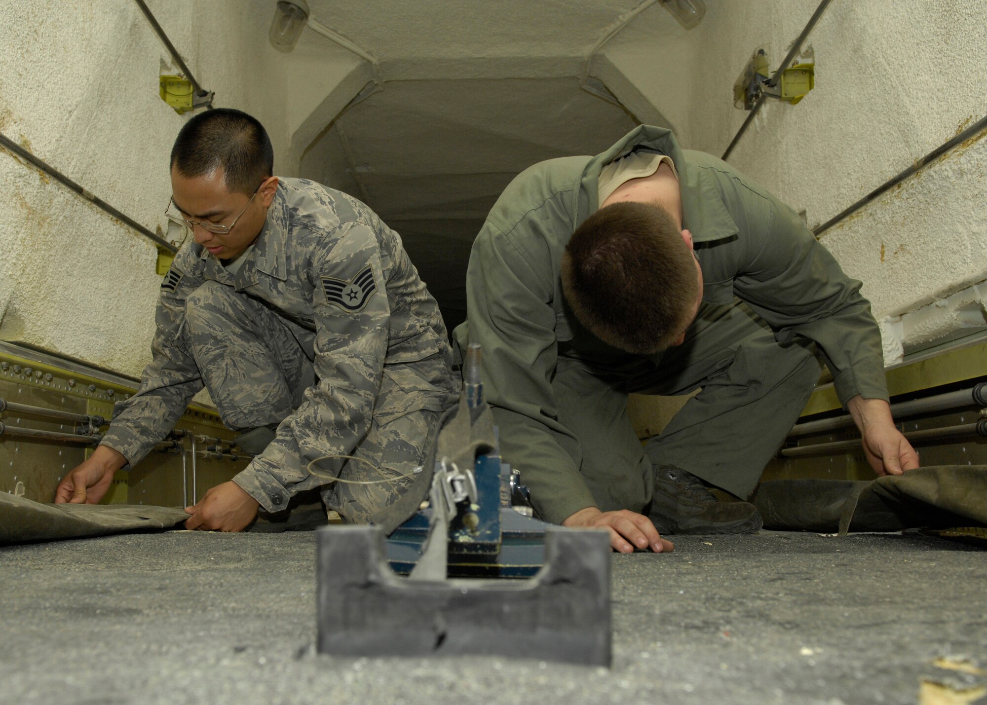 VANDENBERG AIR FORCE BASE, Calif. -- Inside the payload transporter trailer, Staff Sgts. Randy Nepomuceno and Anthony Klatt, both of the 576th Flight Test Squadron, check the vent flaps for leaks and proper air flow here Thursday, March 11, 2010. One of the facility maintainer's numerous jobs is keeping the missile equipment under proper environmental conditions. To do this they use the PT trailer, which is equipped with large air conditioning vents that are powered by the auxiliary power unit situated at the front of the trailer. (U.S. Air Force photo/Airman 1st Class Lael Huss)