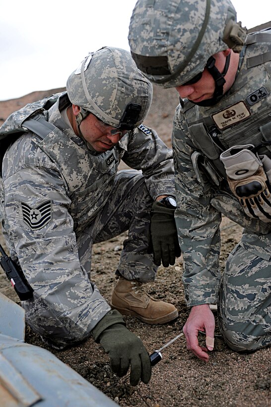 ELLSWORTH AIR FORCE BASE, S.D. -- (Left to right) Tech. Sgt. Jayson Wells, 28th Civil Engineer Squadron explosive ordnance disposal technician, and Senior Airman Travis Few, 28 CES EOD technician, place a MK-2 shape charge against a simulated chemical bomb during a routine training exercise, March 30. The Mk-2 shape charge punctures the chemical bomb, allowing the agent to be released and incinerated by the explosion. (U.S. Air Force photo/Airman 1st Class Matthew Flynn)