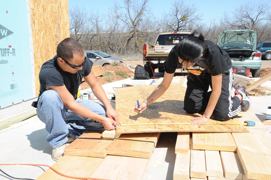 DYESS AIR FORCE BASE, Texas – Airman 1st Class Keith Ammons (left) and Airman Angelica Martinez (right), 7th Communication Squadron, mark a piece of plywood to be cut March 27 as part of a Habitat for Humanity volunteer project. Members from the Airman Advisory Council teamed up with Habitat for Humanity to build a house for the Mendoza family. The project may take several months to complete. (U.S. Air Force photo/ Airman 1st Class Brittney Prescott)