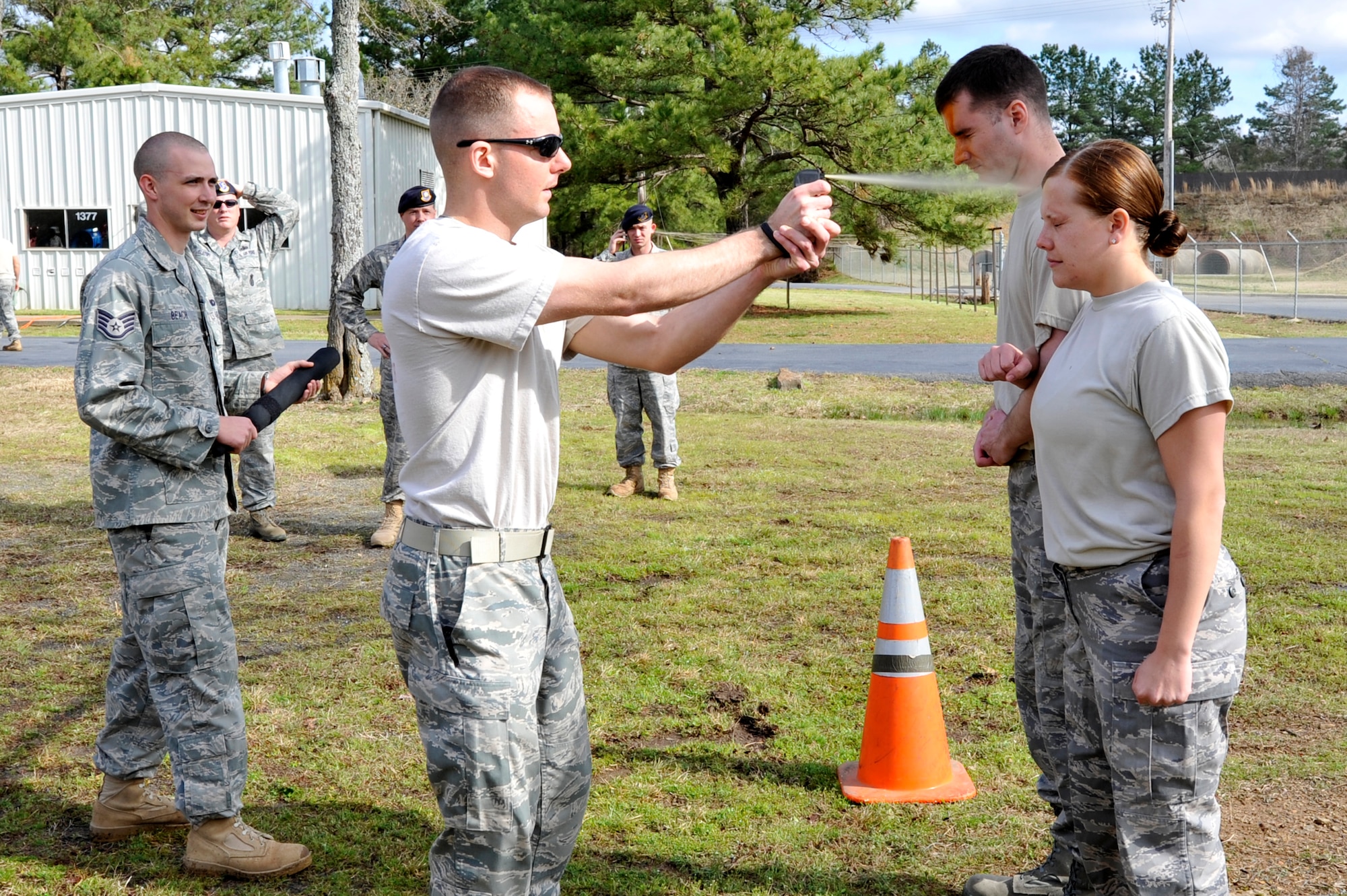 Staff Sgt. Ryan Hook, a 19th Security Forces Squadron trainer, drenches Senior Airman Elizabeth Rosato, a 19th SFS patrolman, with pepper spray while Staff Sgt. Robert Miller waits to begin the tactical course March 25 at Camp Warlord. Contaminated Airmen executed a five-station course before they could wash off the pepper spray. (U.S. Air Force photo by Senior Airman Christine Clark)