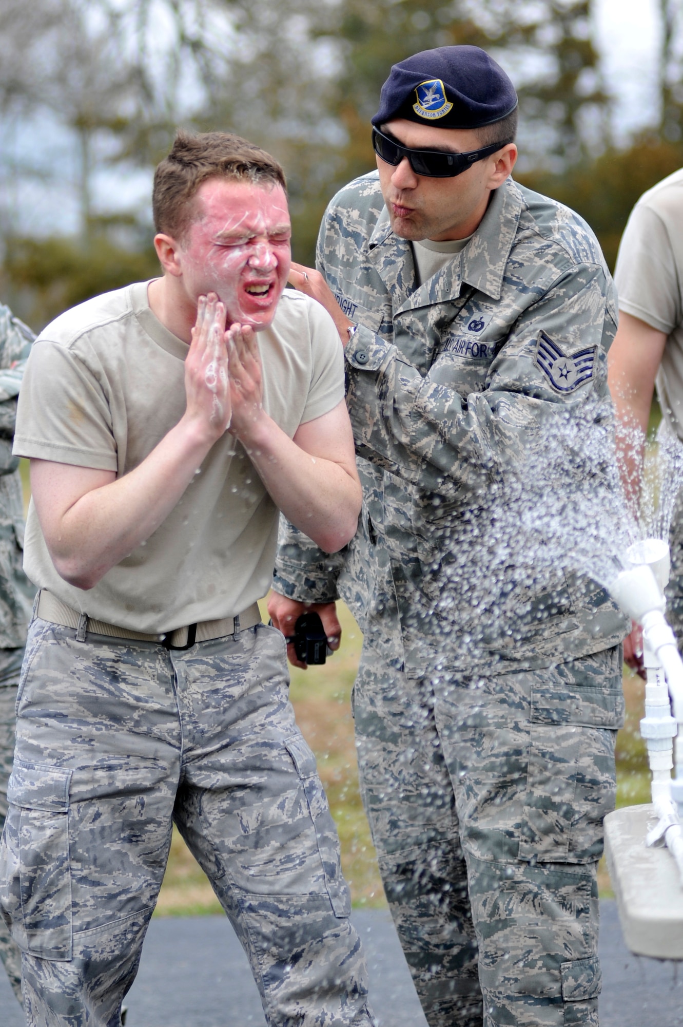 Staff Sgt. Clint Wright, 19th Security Forces Squadron resource advisor, talks Airman 1st Class Nico Hammond, a 19th SFS patrolman, though the pepper spray decontamination process March 25 at Camp Warlord.  After performing the tactical force training while being contaminated with pepper spray, 19th SFS members are eager to decontaminate themselves. (U.S. Air Force photo by Senior Airman Christine Clark)