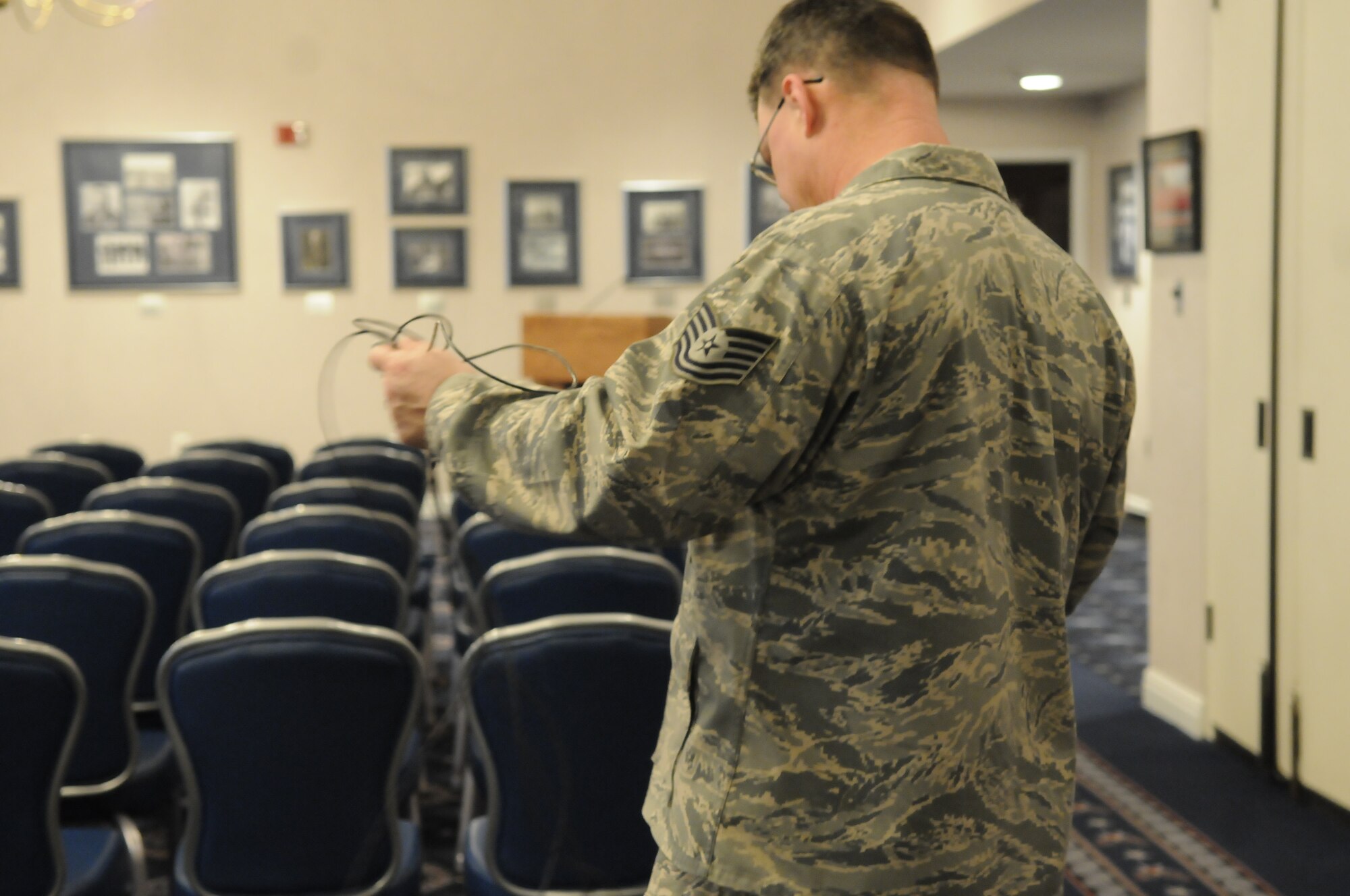 Tech. Sgt. Joe Allen, 744th Communications Squadron, leads microphone wires for a press conference during the Counseil International du Sport Militaire March 28 at the Bolling Club. CISM was founded Feb. 18, 1948 with Belgium, Denmark, France and Luxembourg and the Netherlands representatives signing the original charter. Many organizations from Bolling supported the week-long conference that involved leaders representing 17 countries. (U.S. Air Force photo by Senior Airman Alexandre Montes)