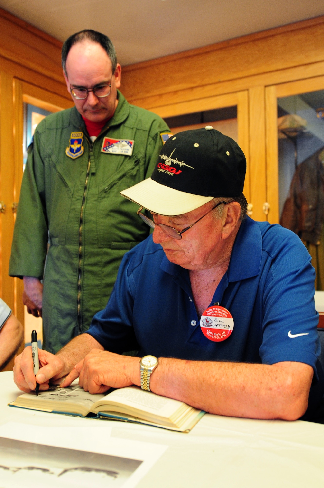 Four Horsemen pioneer, retired Lt. Col. Bill Hatfield, signs the book "Herk: Hero of the Skies" for Master Sgt. Scotty Packard, a 189th Airlift Wing instructor, during a base visit March 26. Sergeant Packard was given the book by his father and shared it with Four Horsemen members to see photos of them taken over 50 years ago. (U.S. Air Force photo by Senior Airman Steele C. G. Britton)