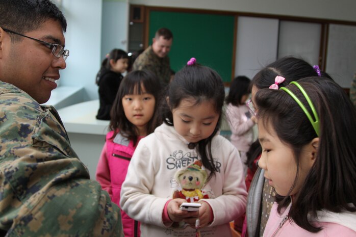 Yechon Air Base, REPUBLIC OF KOREA - Lance Cpl. Victor Contreras, a Foal Eagle participant, plays guitar while one of the students records it on her cell phone during a community relations trip to Yechon Elementary School March 31. During the visit, Marines and sailors taught the students the English alphabet, and played musical chairs and hangman.