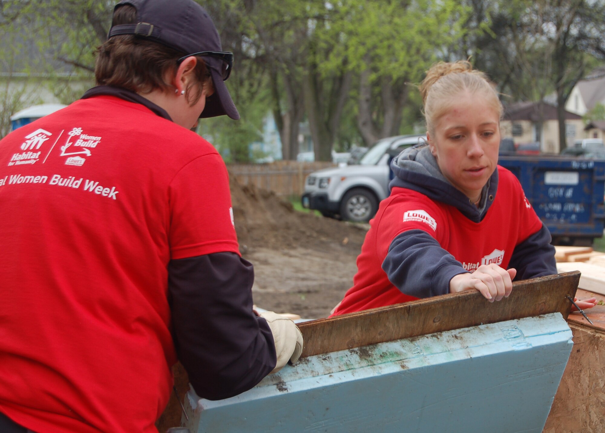 Airman 1st Class Maria Kehoe (left) and Staff Sgt. Elizabeth Fuller both with the 319th Operations Support Squadron, use teamwork to move a piece of plywood from one area to another, May 1. Both Airman Kehoe and Sergeant Fuller are volunteering their time to help build the Red River Valley Habitat for Humanity house in Grand Forks, N.D. The house is being built for single mother Anna Sepeda and her three children. (U.S Air Force photo by 2nd Lt. Anastasia Wasem)