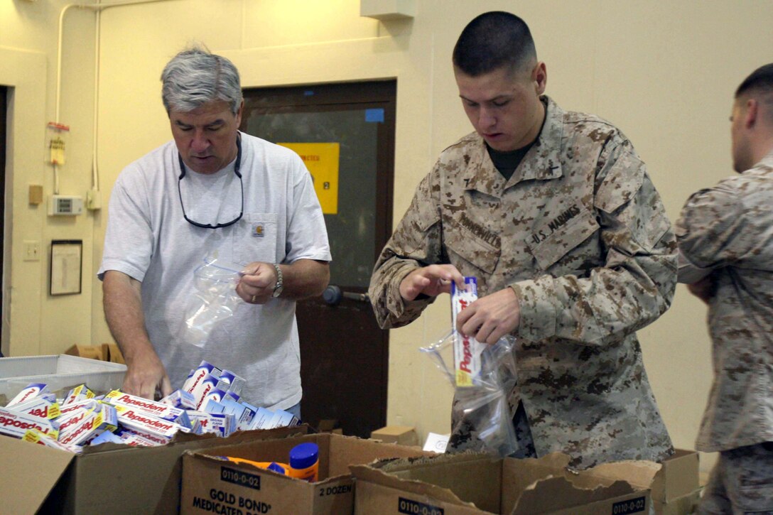 Brian Gallagher and Pfc. Matthew Pommerville, both volunteers with the Operation Caregiver Program, prepare hygiene items for troops in Afghanistan during an Operation Caregiver event at 4th Tank Bn., here May 1.  The program sends care packages to deployed service members two to three times a year. Each Care package contains items such as baby wipes, toothpaste and razors. This event sent more than 1,300 packages to the 7th Marine Regiment in Afghanistan.