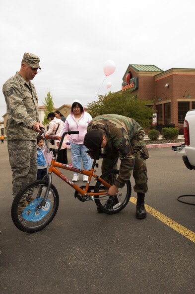 Left, Tech. Sgt. Gary Lezon-Ferreira and Staff Sgt. Gary John work to install training wheels on a bike during the annual Bike?s for Burgers event, May 1st, in Boise, Idaho. This is the eighteenth year members of the Idaho Air National Guard have participated in this community active to provide bikes for underprivileged kids. (U.S. Air Force photo by Staff Sgt. Robert Barney, RELEASED)  