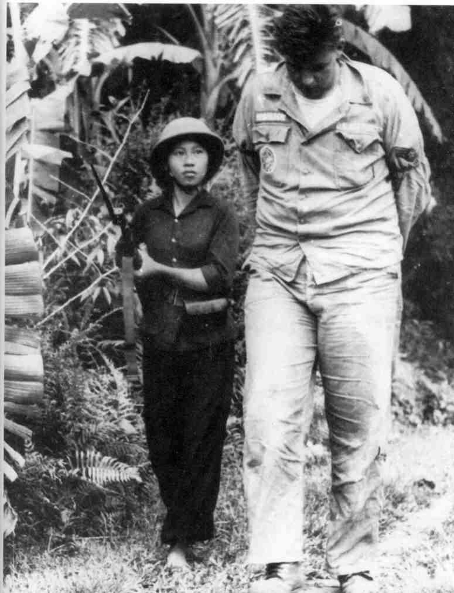 POW Airman First Class Bill Robinson is guarded by a North Vietnamese soldier after his capture on September 20, 1965.  (USAF Photo)