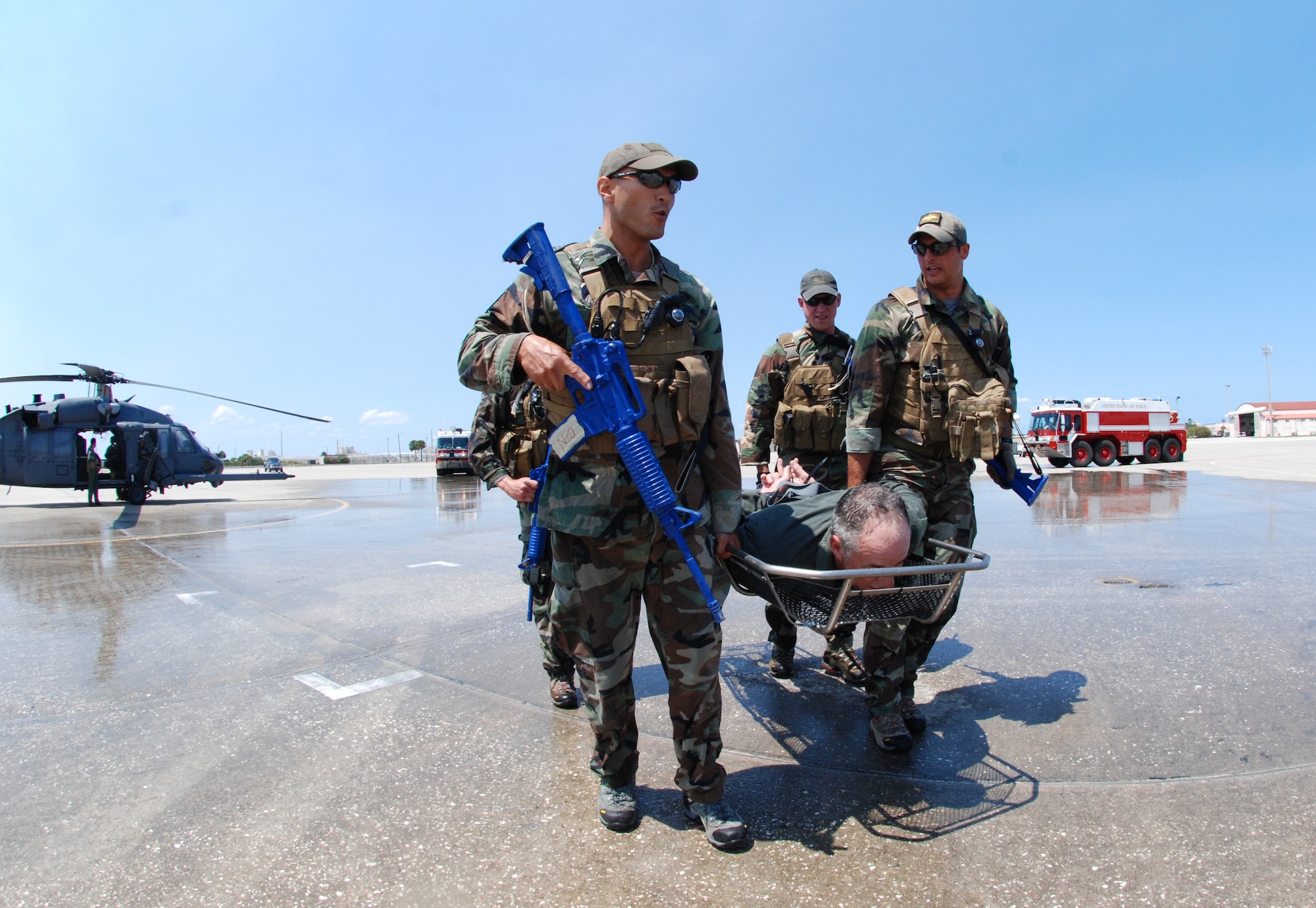 PATRICK AIR FORCE BASE, Fla. - Tech. Sgt. Chris Lais and Senior Airman Brandon Forshaw, both reserve pararescuemen with the 920th Rescue Wing here, lead the way with Colonel Steven Kirkpatrick zip-tied in a stokes litter. Colonel Kirkpatrick was hosed down with water from fire trucks upon getting out of the HH-60G Pave Hawk helicopter after his FINI, or final, flight. (U.S. Air Force photo/Staff Sgt. Leslie Kraushaar)