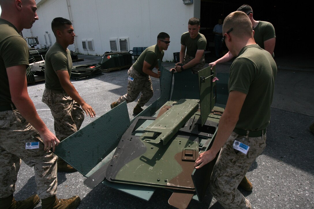 Marines with General Support Motor Transport Company, Combat Logistics Regiment 3, 3rd Marine Logistics Group, III Marine Expeditionary Force, unload humvee up-armor at the Defense Reutilization Management Office receiving warehouse at Camp Kinser April 3. DRMO follows special instruction to dispose of military vehicles.