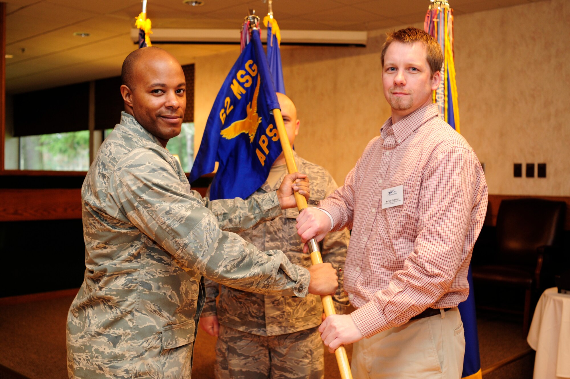 Lt. Col. Will Phillips, 62nd Aerial Port Squadron commander, left, passes the APS guidon to Tom Embleton from FedEx during an honorary change of command ceremony at McChord Field's Clubs and Community Center Feb 12. (U.S. Air Force Photo by Abner Guzman)

