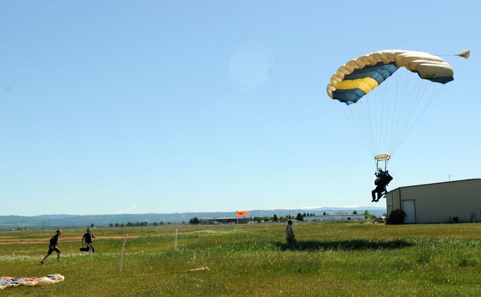 An Airman soars to the ground as skydiving instructors run to catch the parachute and assist in the landing, April 30 at Lincoln Regional Airport. Airmen were skydiving to promote sexual assault awareness during Sexual Assault Awareness month. (Air Force photo by Airman 1st Class David Tracy)
