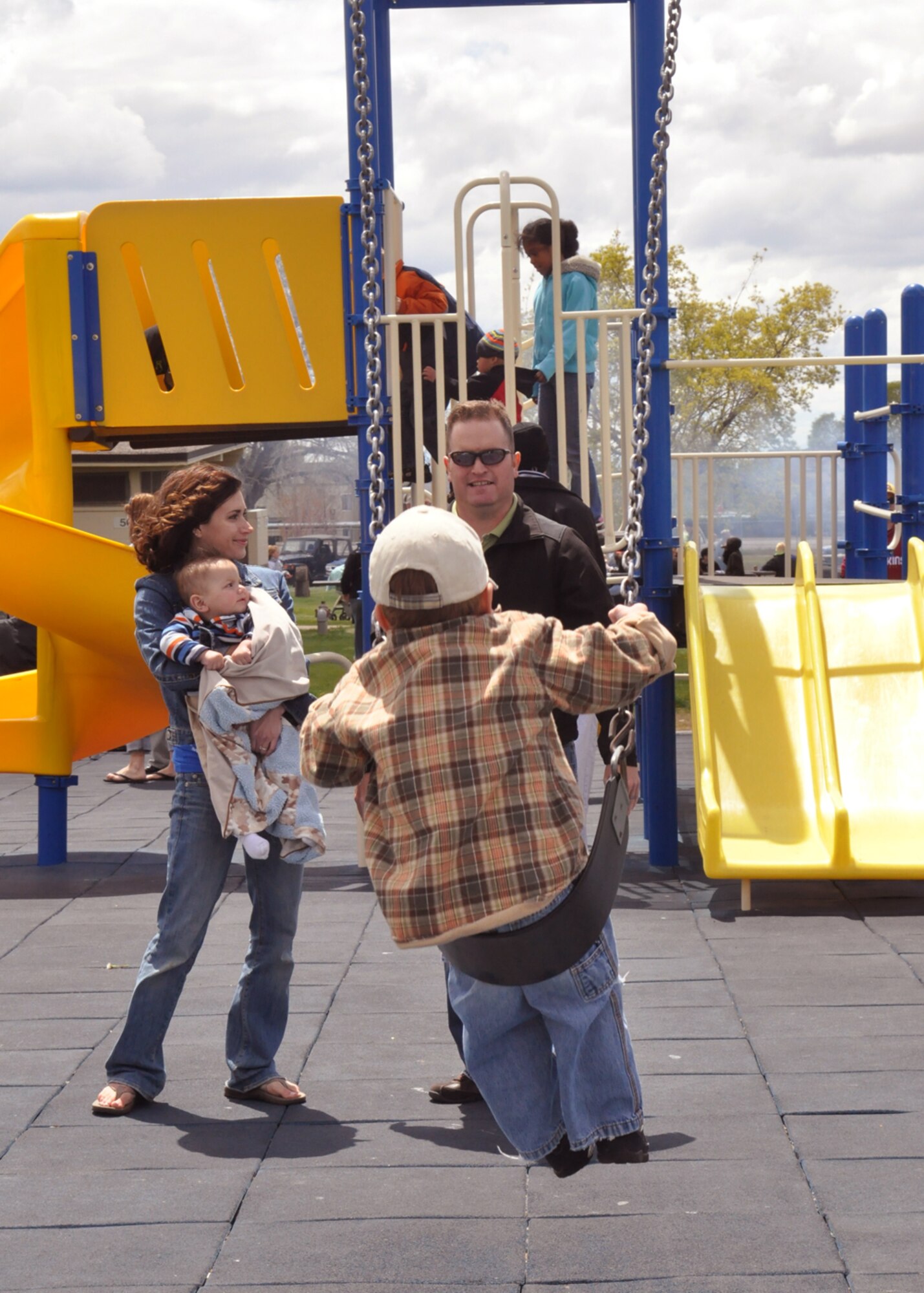 Maj. Jason Henrie, 419th Communication Squadron, pushes his four-year-old, Cutler, on the swings while wife, Natalie, stands by during the wing’s Family Day at Centennial Park May 2. (U.S. Air Force photo/Staff Sgt. Heather Skinkle)