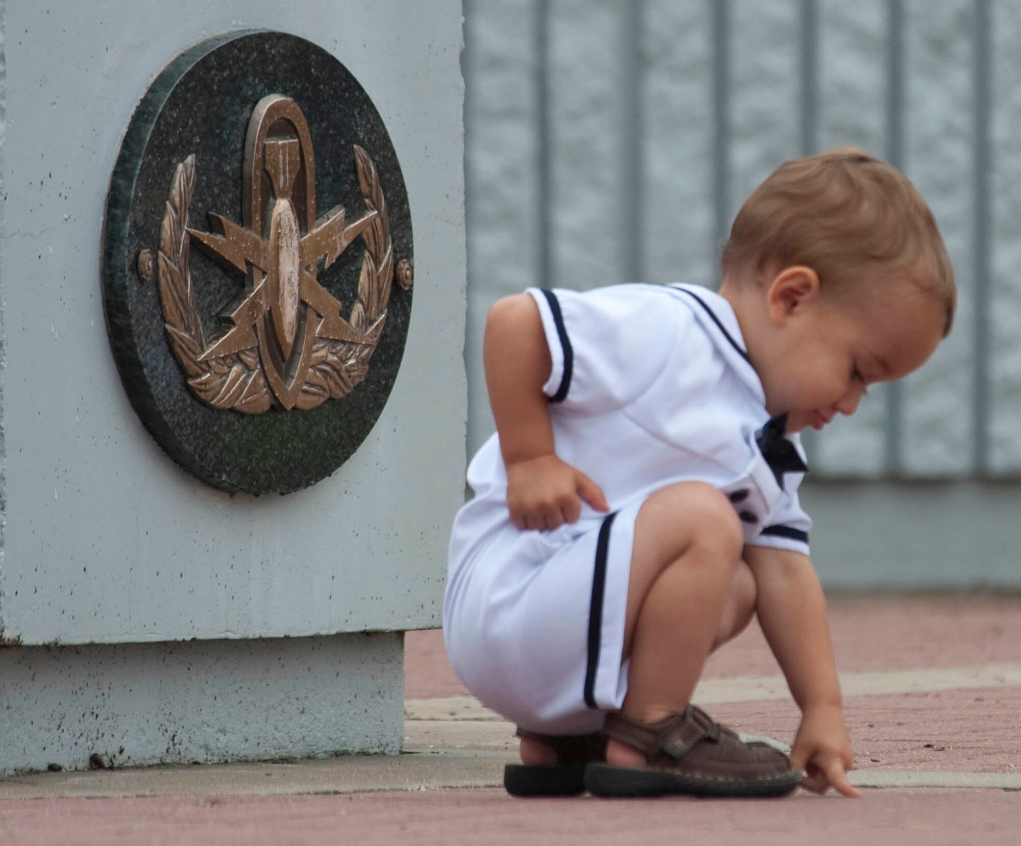 A young boy points to a name on the brick walkway during the Explosive Ordnance Disposal memorial service May 1. (USAF photo/Greg Murry)