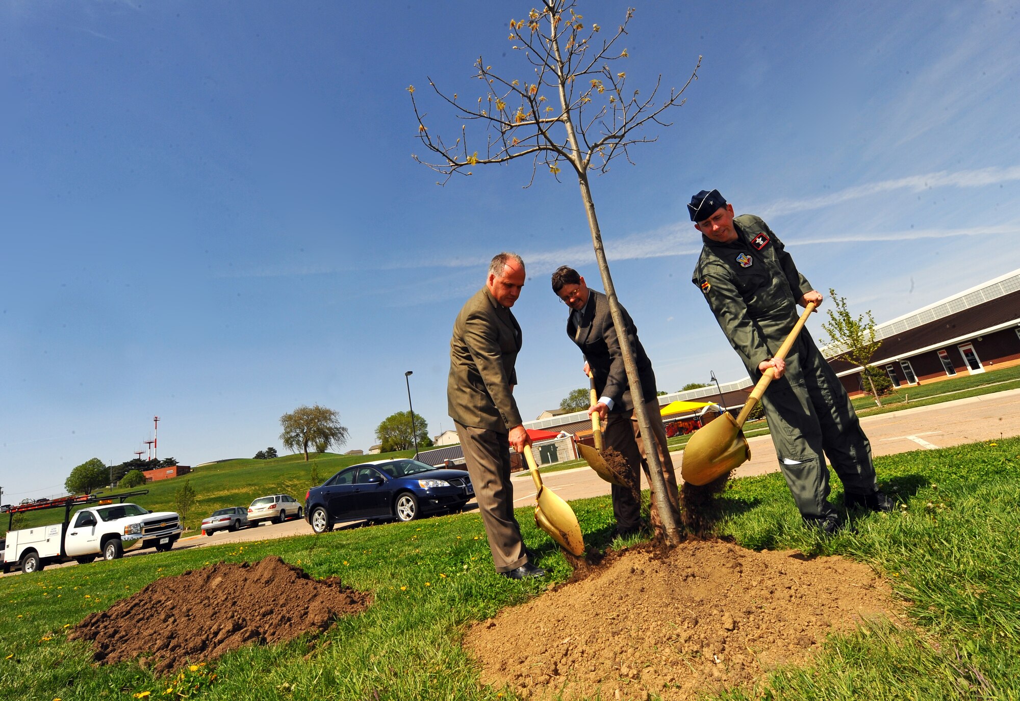 OFFUTT AIR FORCE BASE, Neb. -- From left to right, John Kundinger, deputy commander of the 55th Mission Support Group, Mark Jacobsen, 55th Civil Engineering Squadron commander and Brig. Gen. John N.T. Shanahan, 55th Wing commander, take ceremonial golden shovels and place dirt at the base of a newly planted Northern Red Oak tree in front of Child Development Center II here April 29 in celebration of Arbor Day. Offutt has been named Tree City USA for the last 22 years by the Arbor Day Foundation. U.S. Air Force photo by Josh Plueger