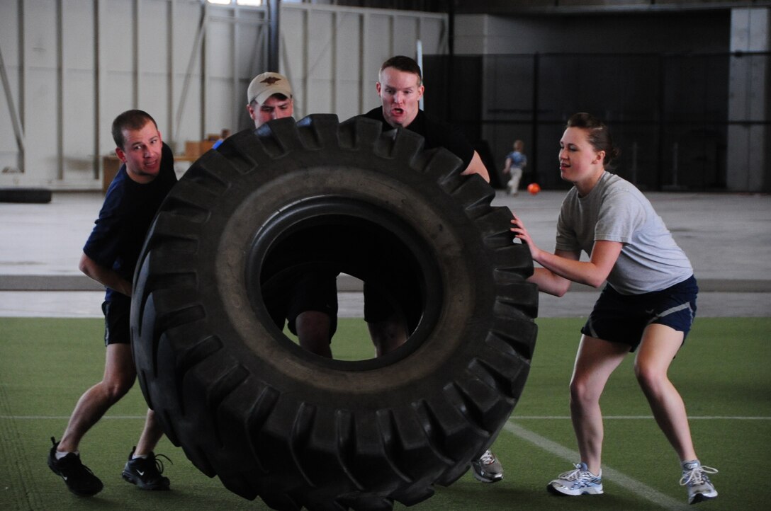 ELLSWORTH AIR FORCE BASE, S.D. – (Left to right) Capt. Todd Patterson, 28th Operations Support Squadron flight commander, Senior Airman Zachary Yoakam, 28th Operations Group survival, evasion, resistance and escape specialist, Staff Sgt. Brandon Dunphy, 28 OG SERE NCO in-charge and Airman 1st Class Alison Meyer, 28 OG intelligence analyst, work together in a tire flip event, April 29.  The tire-flip event was part of the quarterly Iron Flight competition where this team took 2nd place. (U.S. Air Force photo/Airman 1st Class Anthony Sanchelli)
