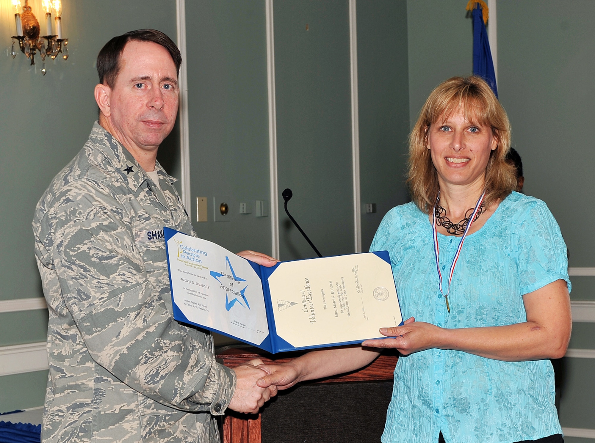 OFFUTT AIR FORCE BASE, Neb. -- Brig. Gen. John N.T. Shanahan, 55th Wing commander, presents the Volunteer Excellence Award to Mary Burden, an account manager for the 55th WG Chapel, during the Volunteer Appreciation Reception at the Patriot Club here April 28. More than 80 people from various organizations on and off-base attended the event to honor the contributions of Offutt's many volunteers. Mrs. Burden, the spouse of Master Sgt. Ken D. Burden, crew chief section chief with the 55th Maintenance Group, volunteered more than 380 hours in 2009 to support the chapel in a number of ways. U.S. Air Force photo by Charles Haymond