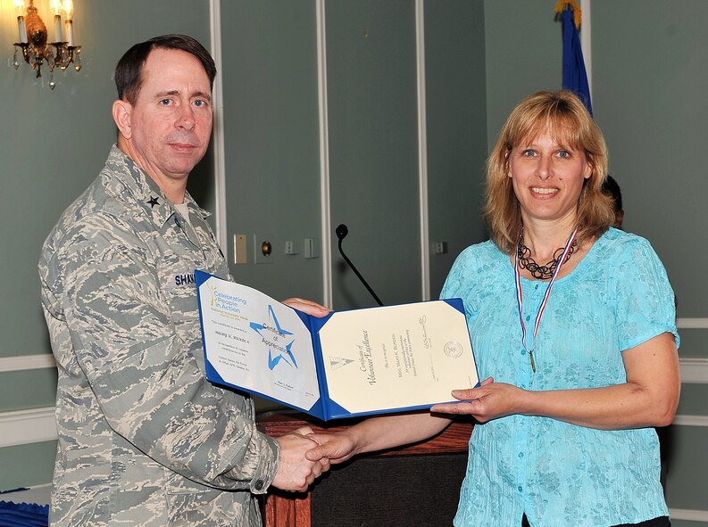 OFFUTT AIR FORCE BASE, Neb. -- Brig. Gen. John N.T. Shanahan, 55th Wing commander, presents the Volunteer Excellence Award to Mary Burden, an account manager for the 55th WG Chapel, during the Volunteer Appreciation Reception at the Patriot Club here April 28. More than 80 people from various organizations on and off-base attended the event to honor the contributions of Offutt's many volunteers. Mrs. Burden, the spouse of Master Sgt. Ken D. Burden, crew chief section chief with the 55th Maintenance Group, volunteered more than 380 hours in 2009 to support the chapel in a number of ways. U.S. Air Force photo by Charles Haymond