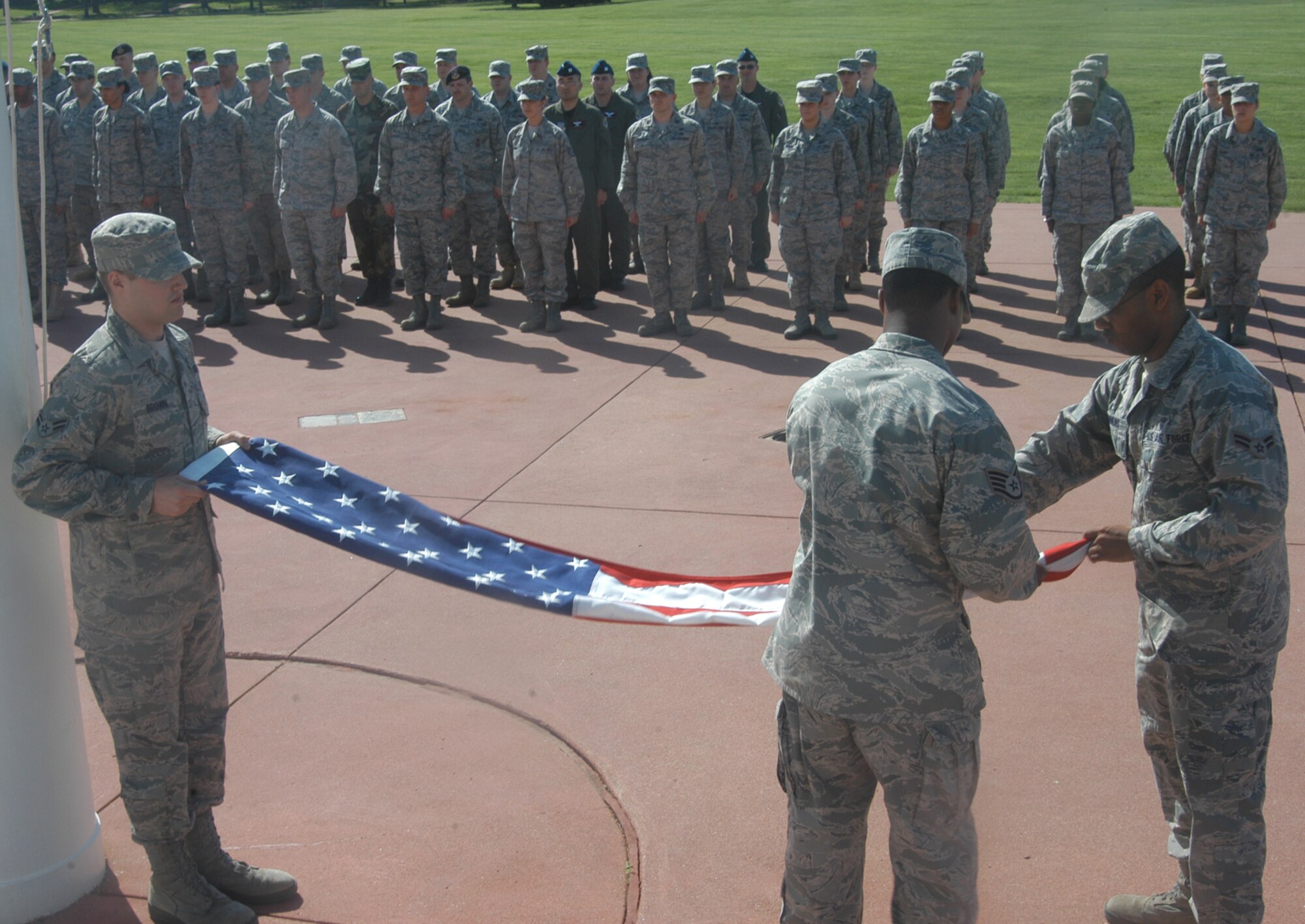 OFFUTT AIR FORCE BASE, Neb. -- Staff Sgt. Julius McCray, Airman First Class Darius T. Dinkins and Airman 1st Class Dylan Brown, all with the 55th Comptroller Squadron, carefully fold the American flag at the parade grounds here, as several members of the 55th Wing look on, during a retreat ceremony April 29. The ceremony signifies the end of the duty day. U.S. Air Force photo by Staff Sgt. James M. Hodgman
